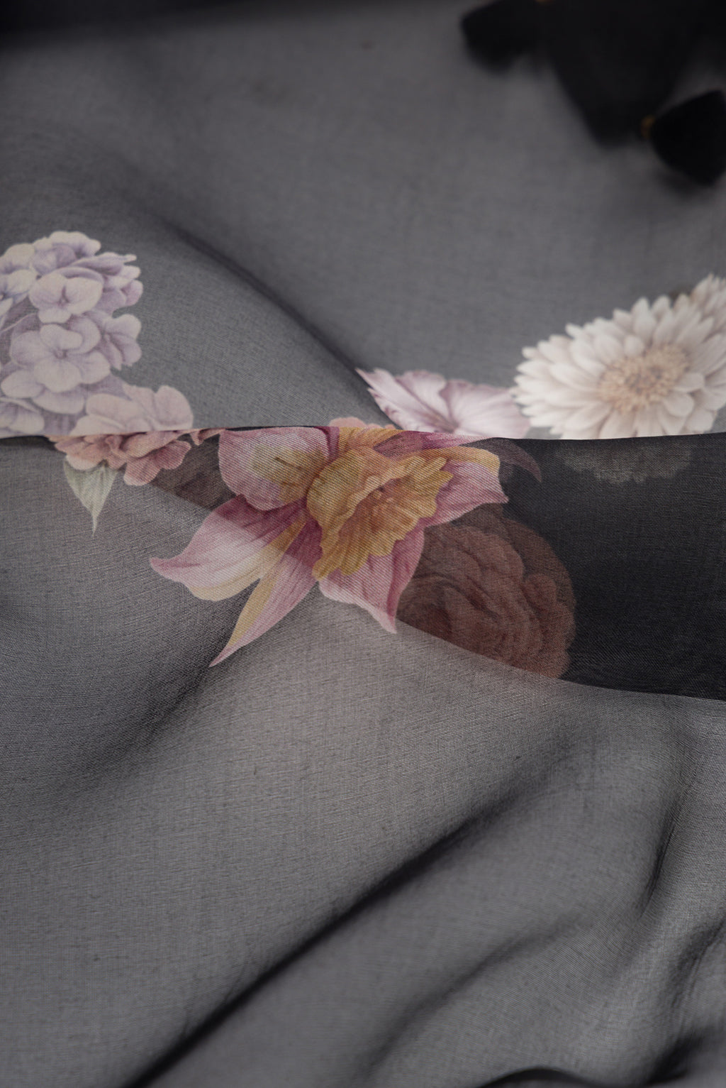Close up of Black Dual Tone Organza Silk Saree with Printed design on the body and Printed Border.  displaying folds