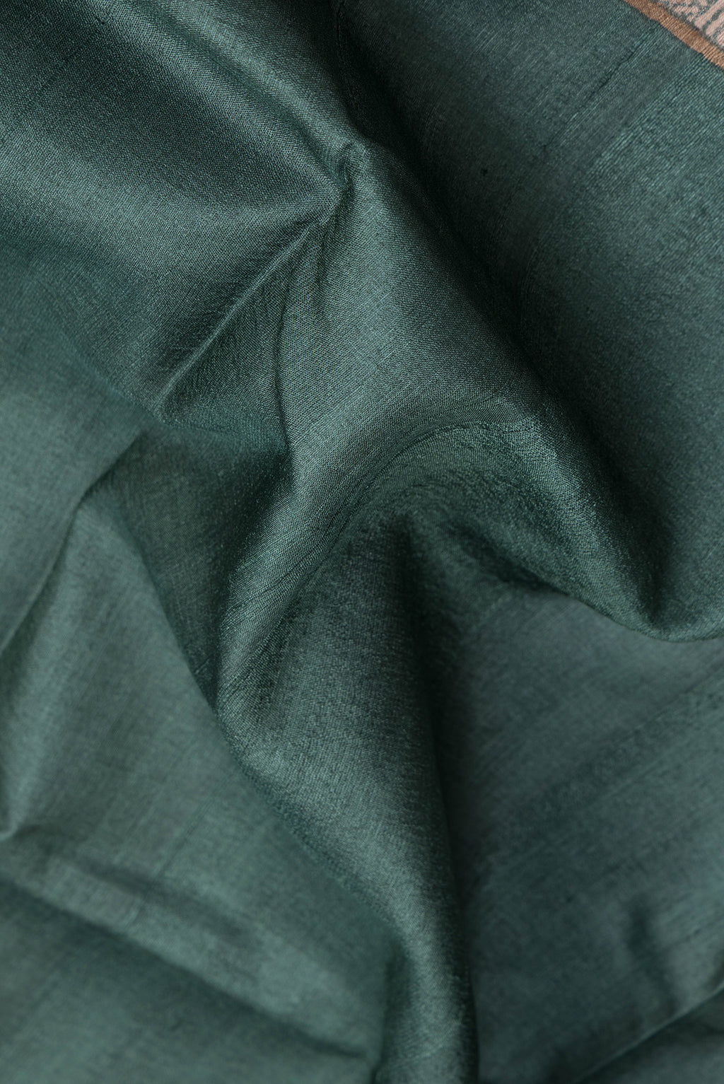 Close up of Green Dual Tone Tussar Silk Saree with Plain Body and Fancy Border.  displaying folds