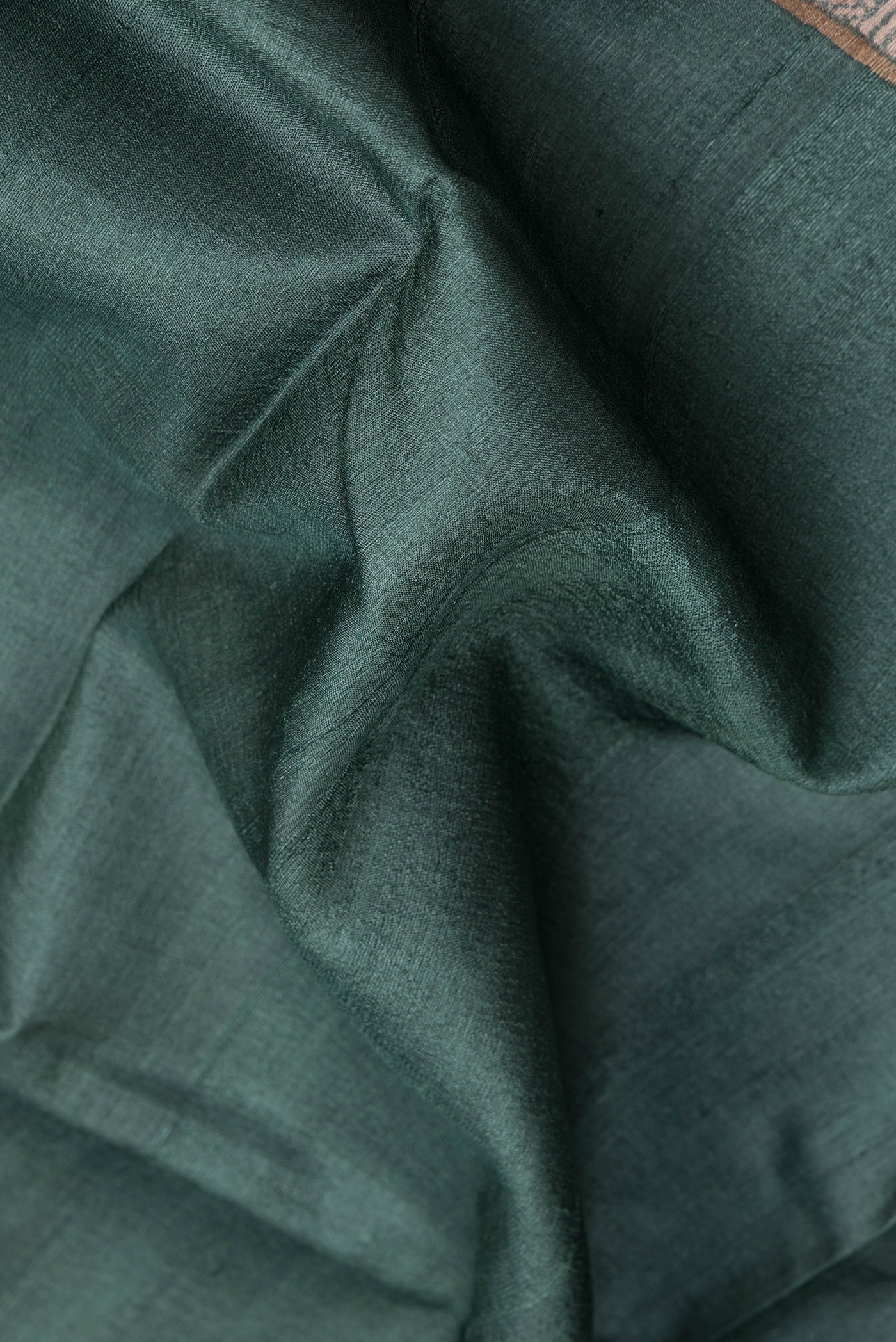 Close up of Green Dual Tone Tussar Silk Saree with Plain Body and Fancy Border.  displaying folds