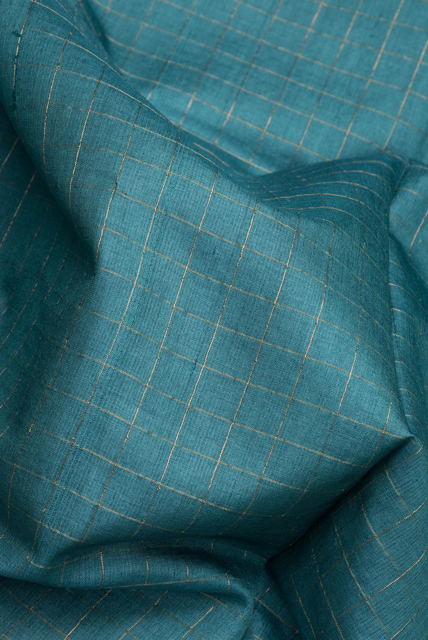 Close up of Peacock Blue Dual Tone Tussar Silk Saree with Checked design on the body and Printed Border.  displaying folds