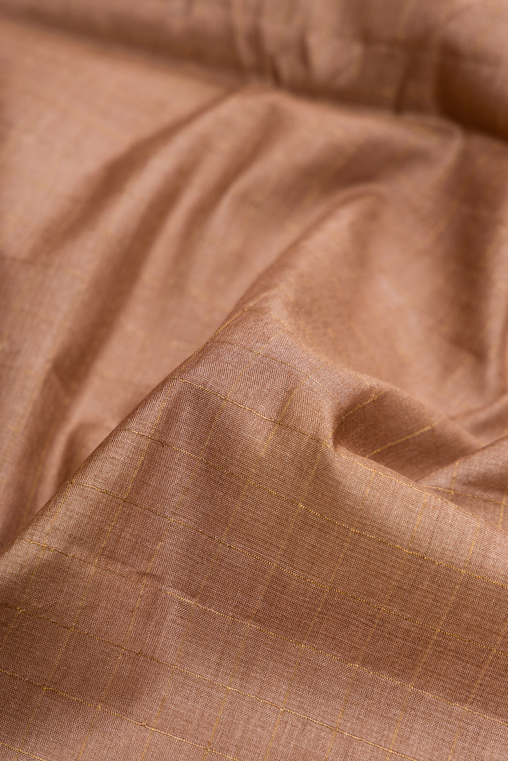 Close up of Brown Dual Tone Tussar Silk Saree with Checked design on the body and Printed Border.  displaying folds