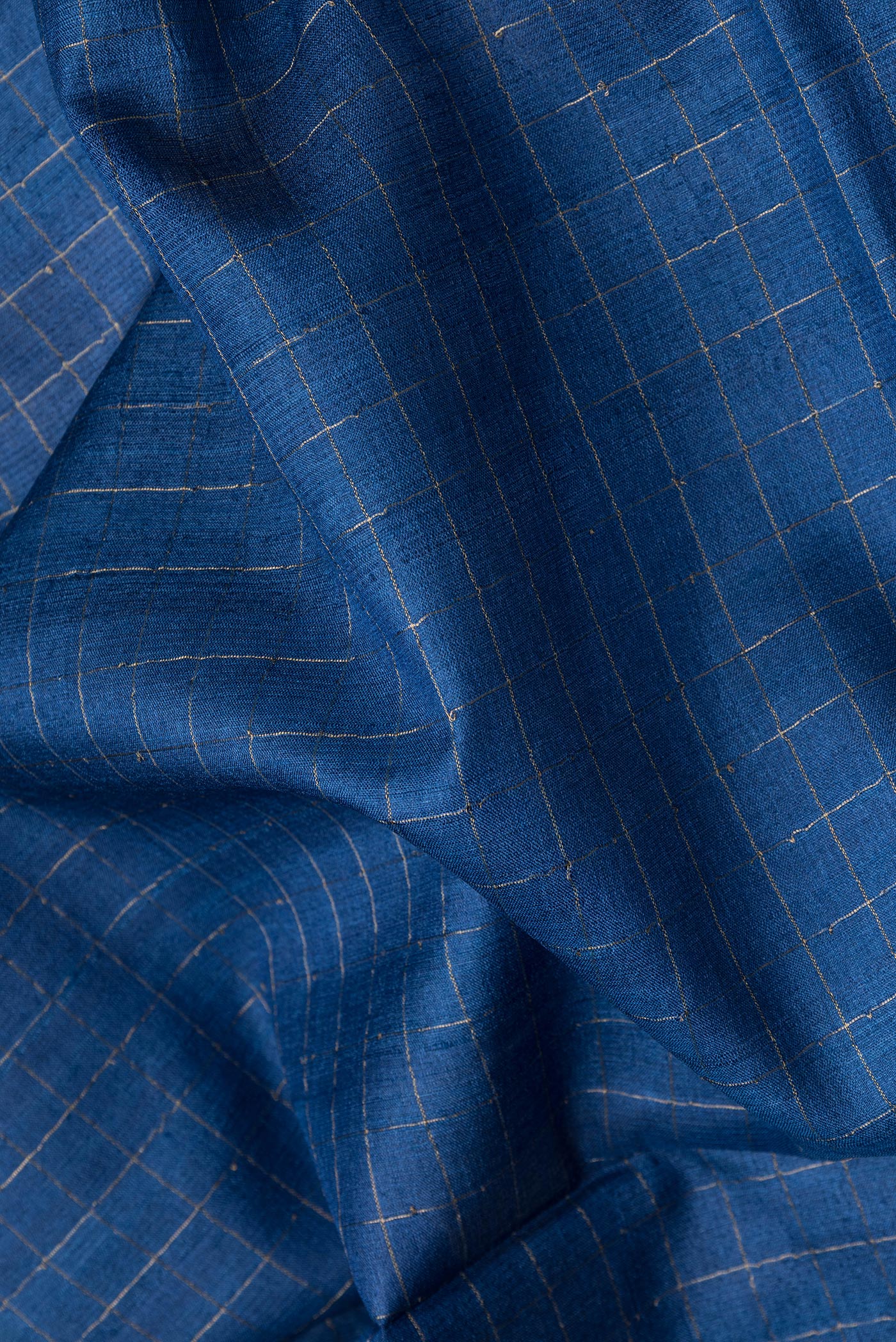 Close up of Royal Blue Dual Tone Tussar Silk Saree with Checked design on the body and Printed Border.  displaying folds