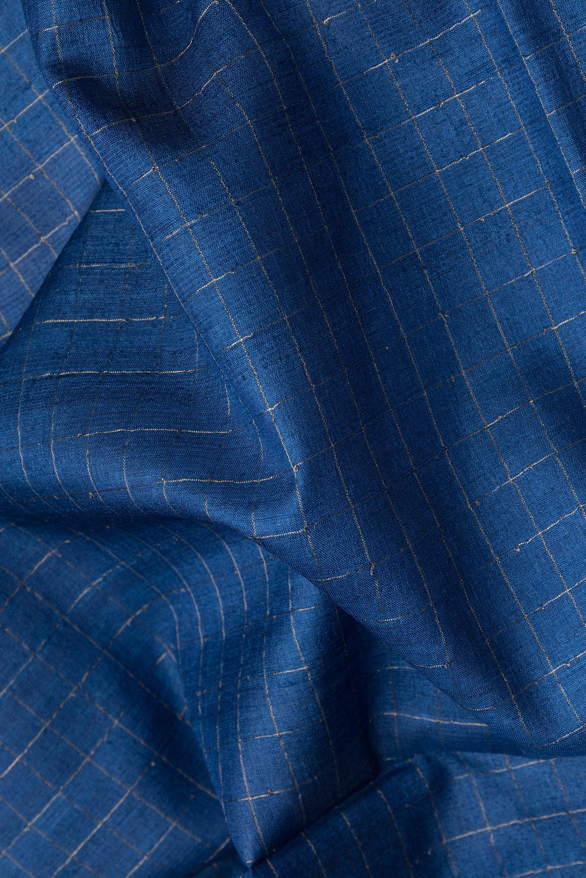 Close up of Royal Blue Dual Tone Tussar Silk Saree with Checked design on the body and Printed Border.  displaying folds