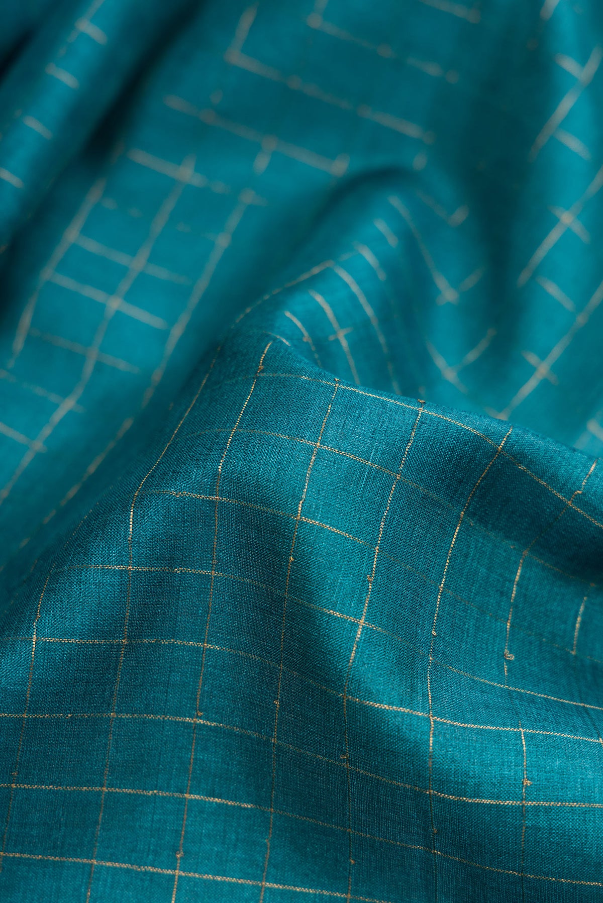 Close up of Peacock Blue Dual Tone Tussar Silk Saree with Checked design on the body and Printed Border.  displaying folds