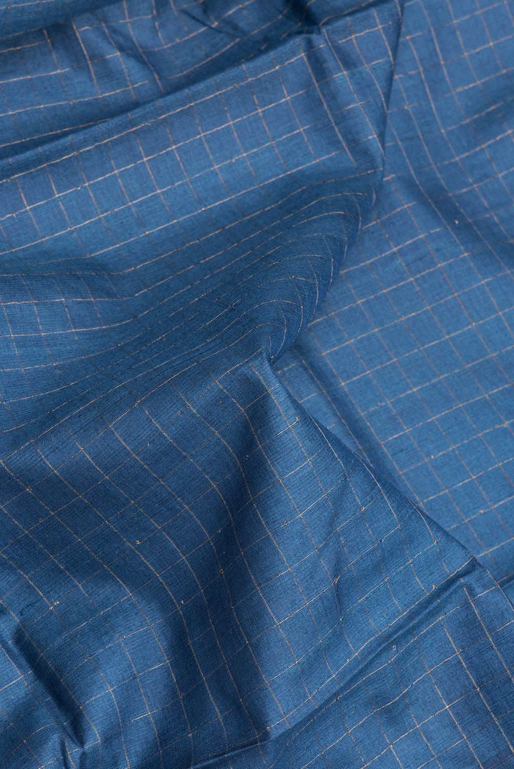 Close up of Peacock Blue Tussar Silk Saree with Checked design on the body and Printed Border.  displaying folds