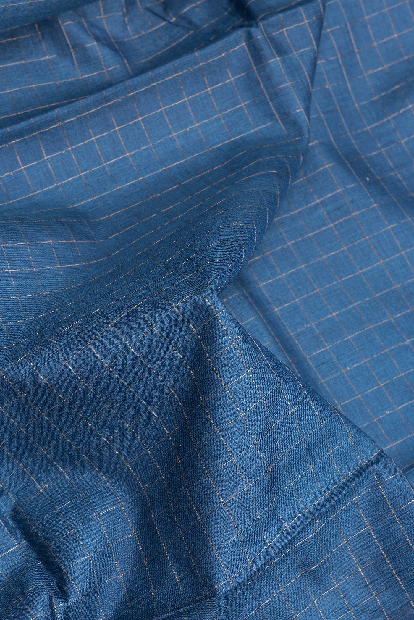 Close up of Peacock Blue Tussar Silk Saree with Checked design on the body and Printed Border.  displaying folds