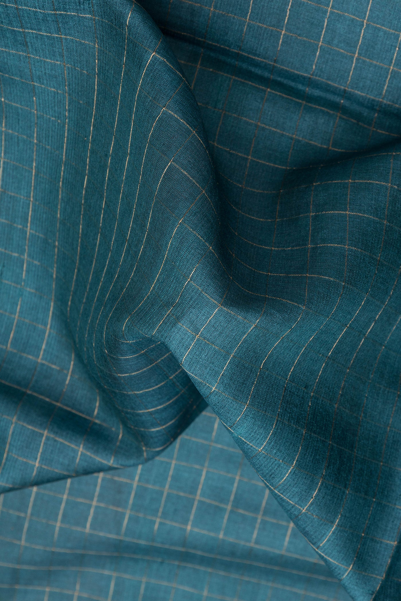 Close up of Peacock Blue Dual Tone Tussar Silk Saree with Checked design on the body and Printed Border.  displaying folds