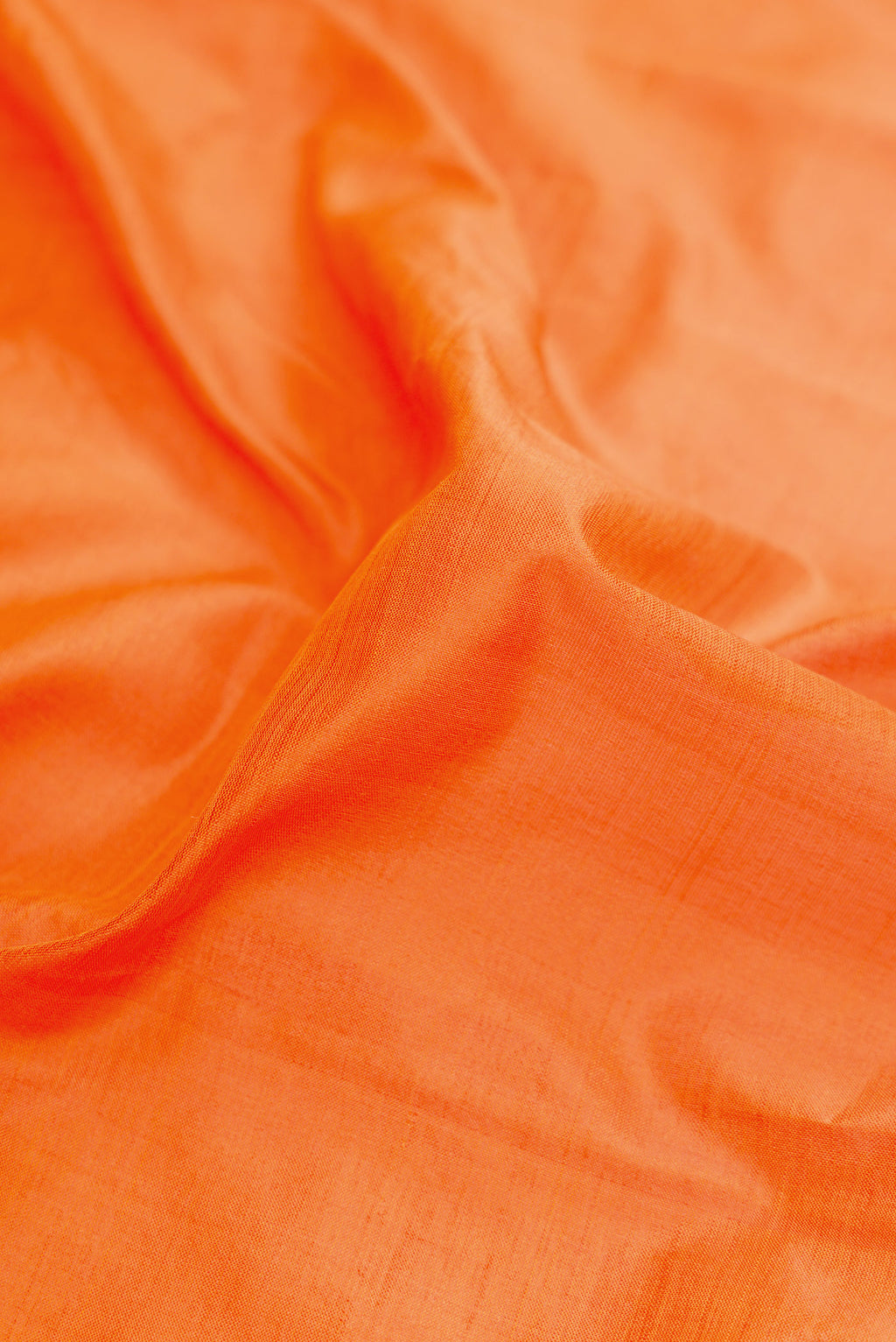 Close up of Orange Dual Tone Kanchipuram Silk Saree with Plain Body and Zari Border.  displaying folds
