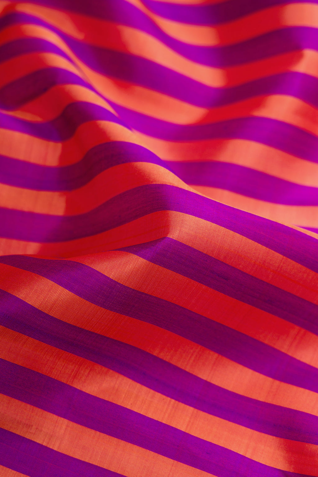 Close up of Purple and Brick Orange Color Kanchipuram Silk Saree with Stripes on the body and Zari Border.  displaying folds