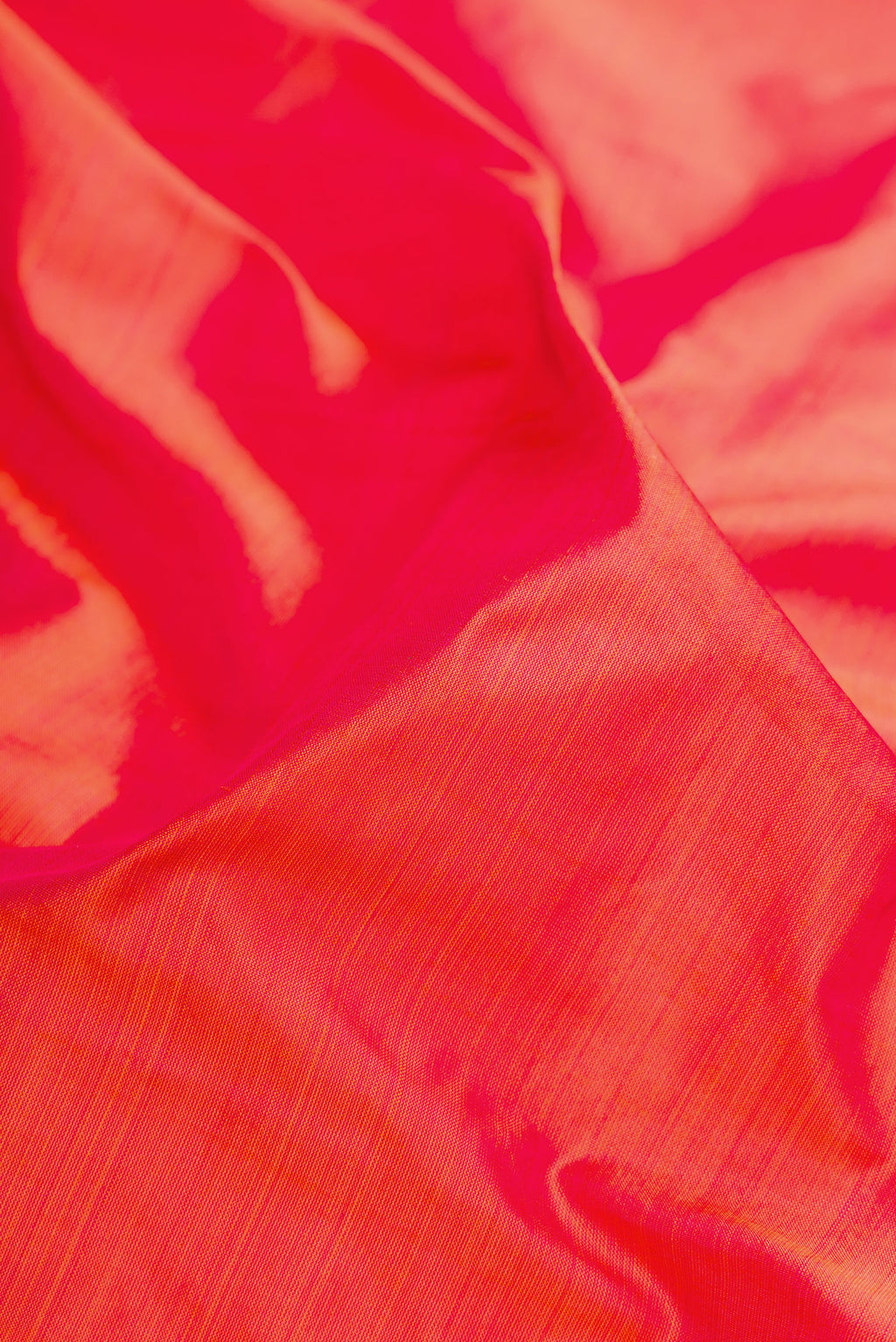 Close up of Coral Dual Tone Kanchipuram Silk Saree with Plain Body and Zari Border.  displaying folds