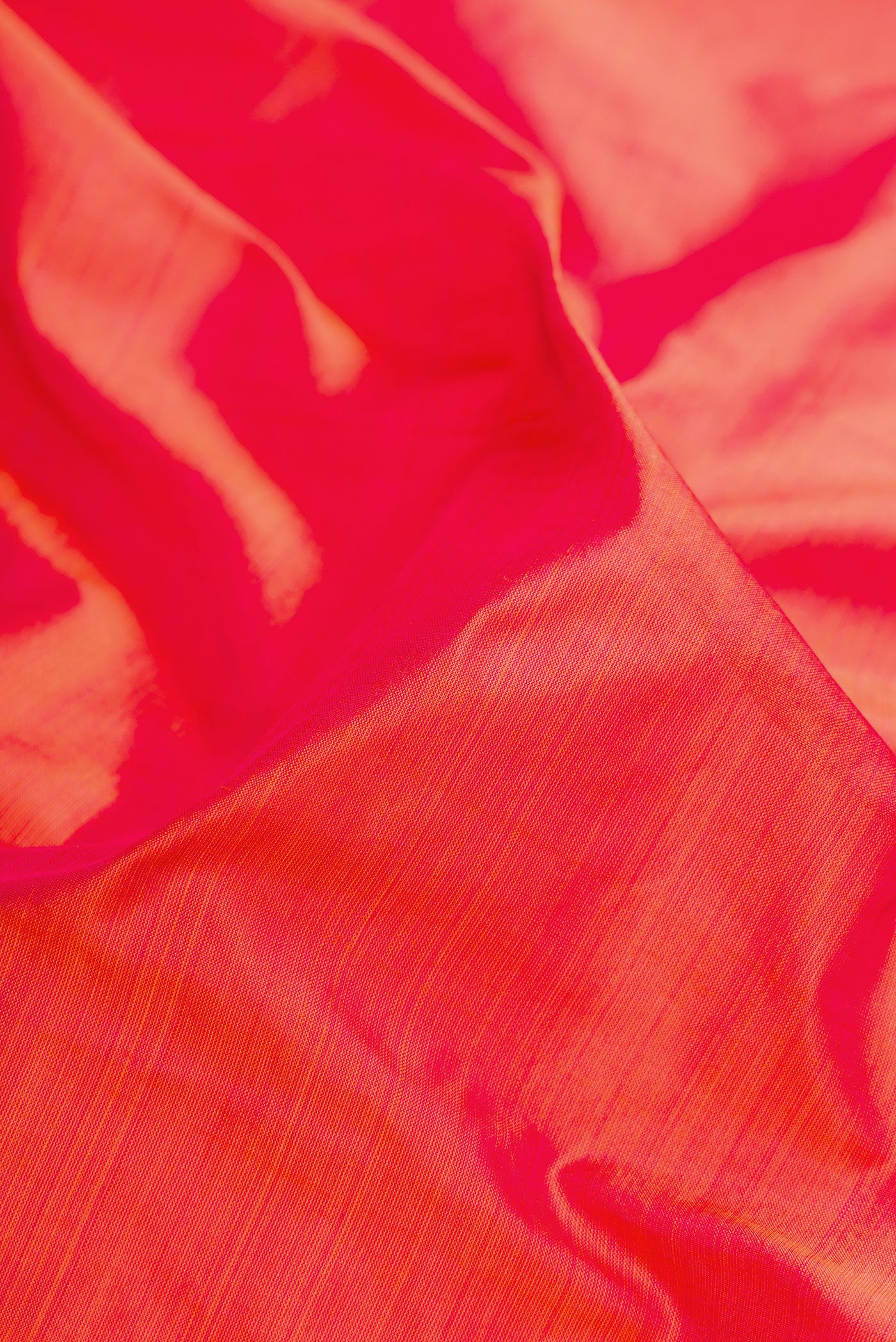 Close up of Coral Dual Tone Kanchipuram Silk Saree with Plain Body and Zari Border.  displaying folds