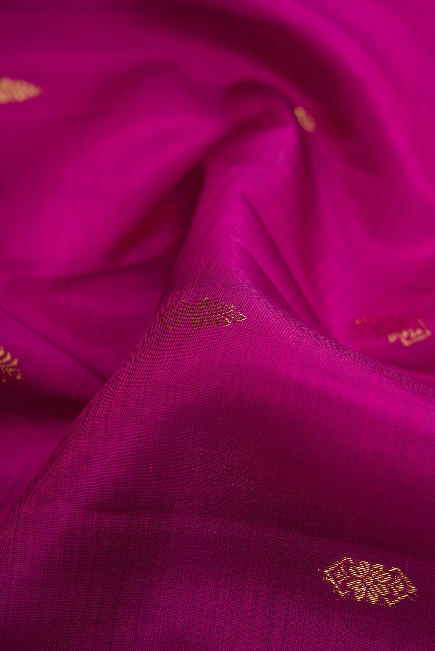 Close up of Magenta Dual Tone Kanjivaram Silk Saree with Zari Butta on the body and Zari Border.  displaying folds
