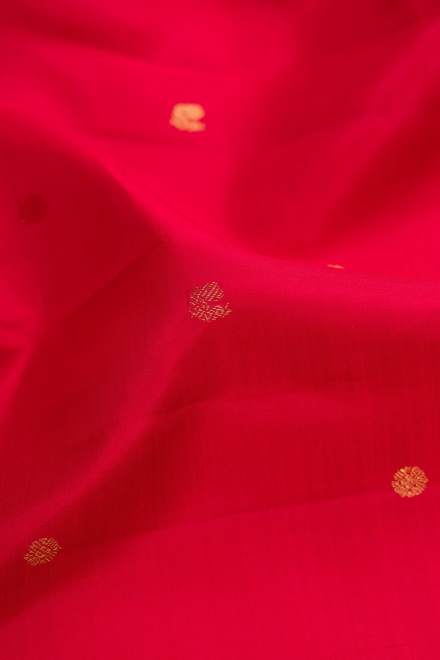 Close up of Red Dual Tone Kanjivaram Silk Saree with Zari Butta on the body and Zari Border.  displaying folds