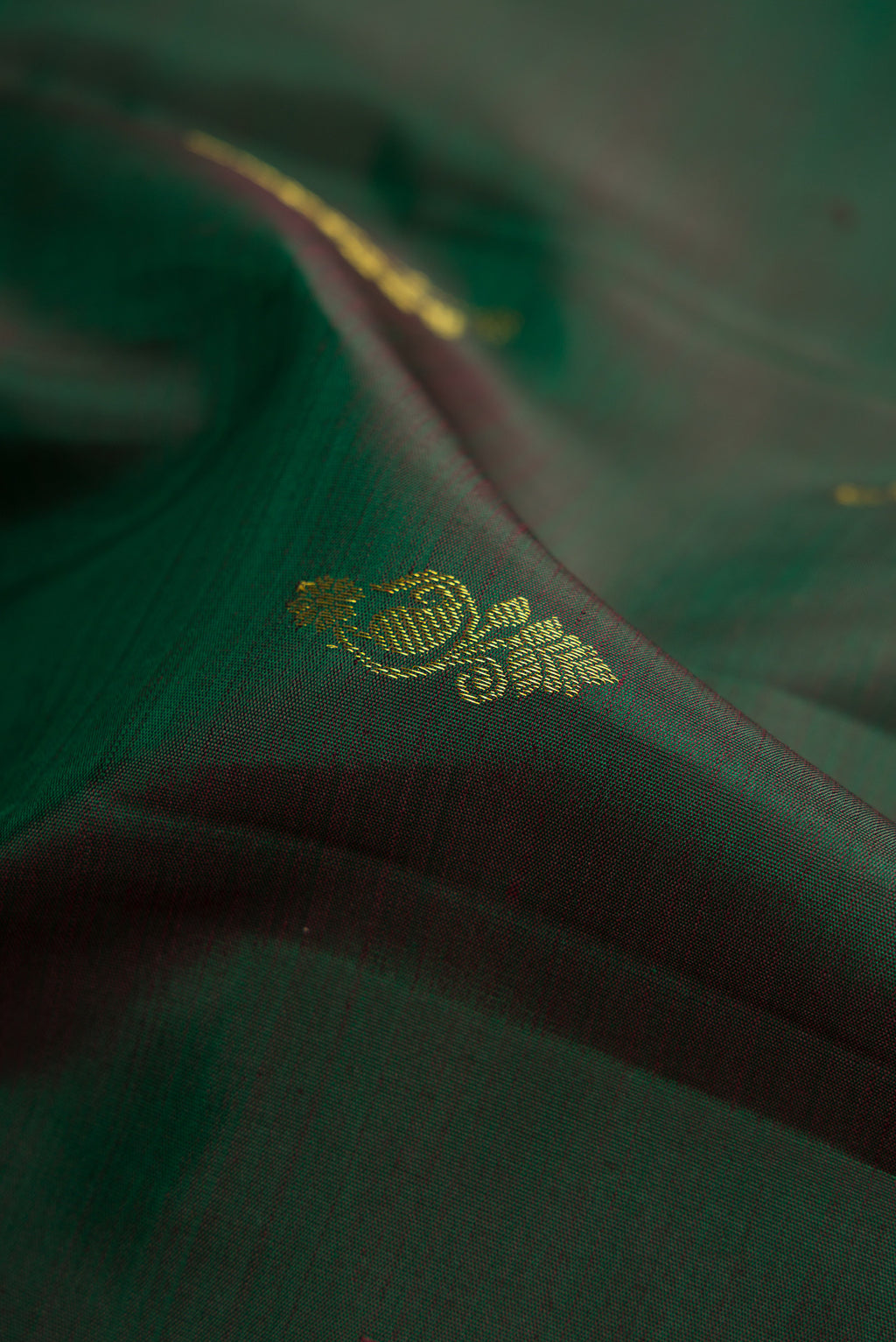 Close up of Bottle Green Dual Tone Kanjivaram Silk Saree with Zari Butta on the body and Zari Border.  displaying folds