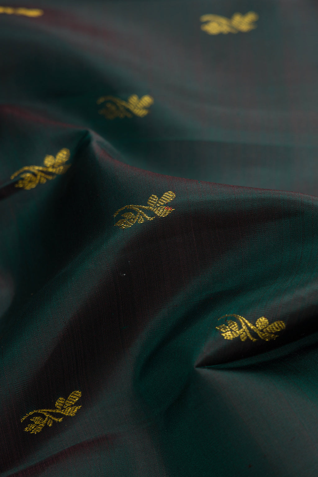 Close up of Bottle Green Dual Tone Kanjivaram Silk Saree with Zari Butta on the body and Zari Border.  displaying folds