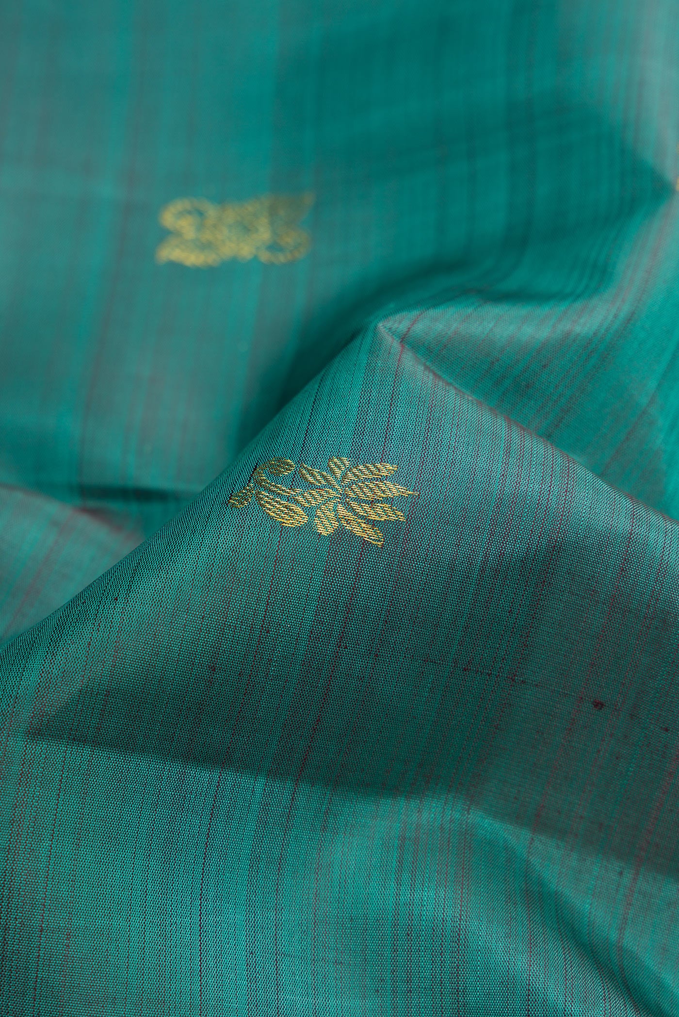 Close up of Teal Dual Tone Kanjivaram Silk Saree with Zari Butta on the body and Zari Border.  displaying folds