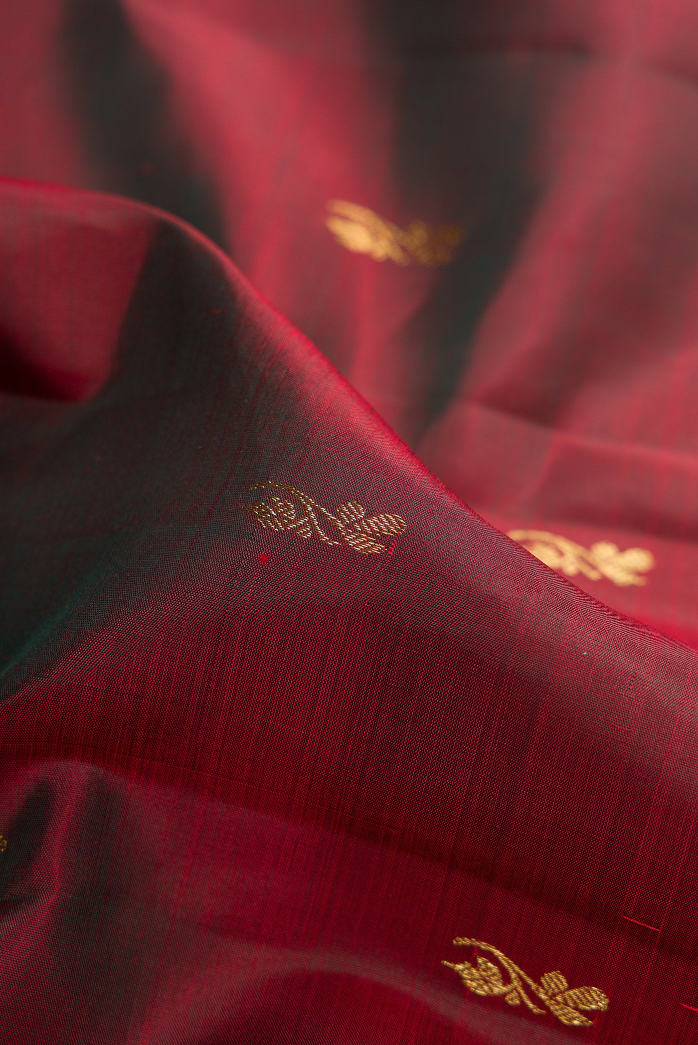 Close up of Maroon Dual Tone Kanjivaram Silk Saree with Zari Butta on the body and Zari Border.  displaying folds