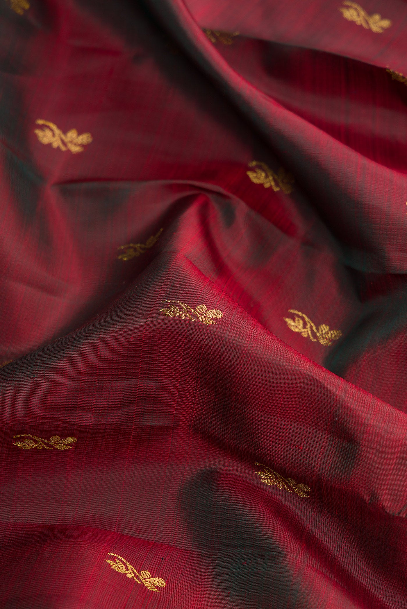 Close up of Maroon Dual Tone Kanjivaram Silk Saree with Zari Butta on the body and Zari Border.  displaying folds