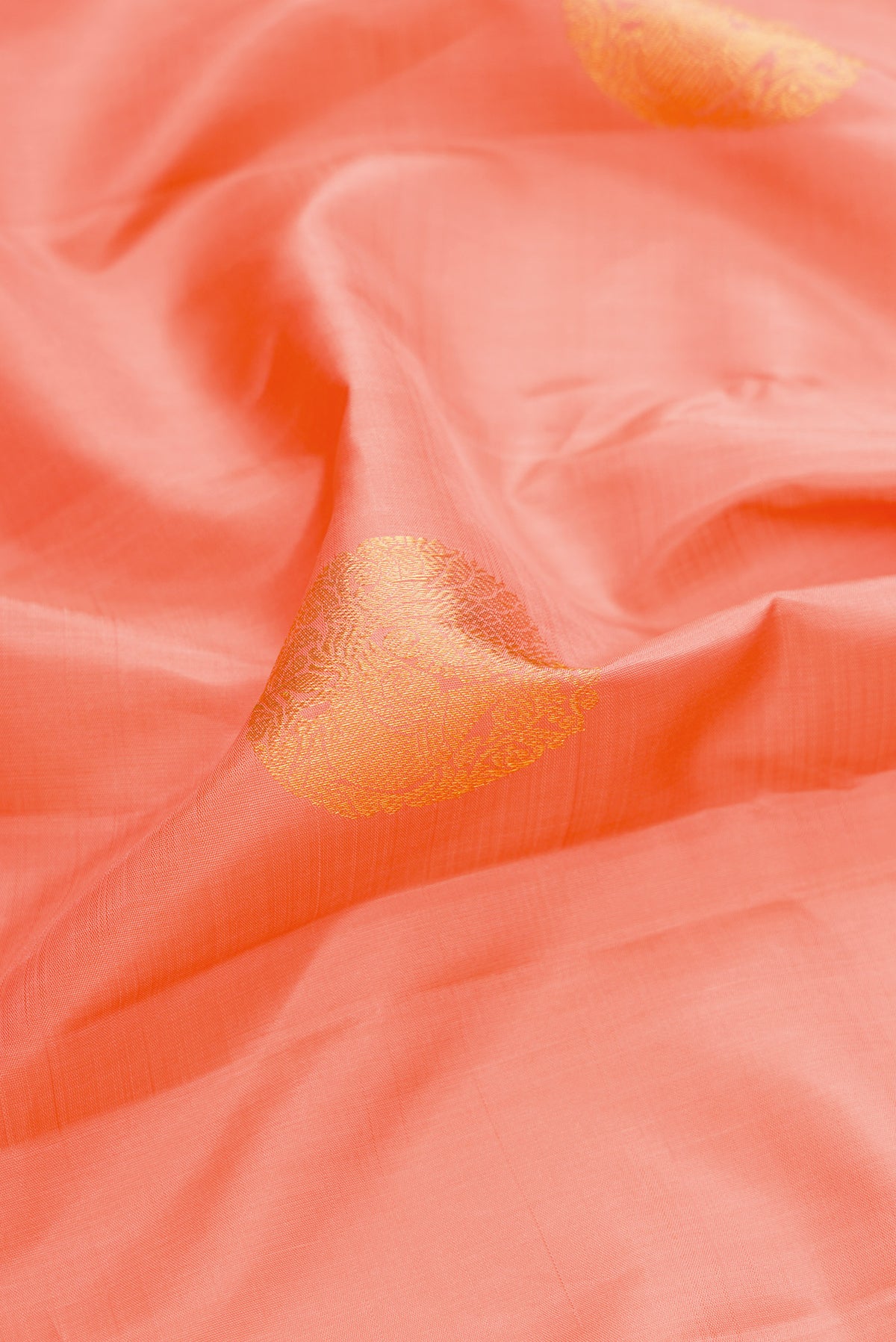 Close up of Peach Dual Tone Kanjivaram Silk Saree with Zari Butta on the body and Zari Border.  displaying folds