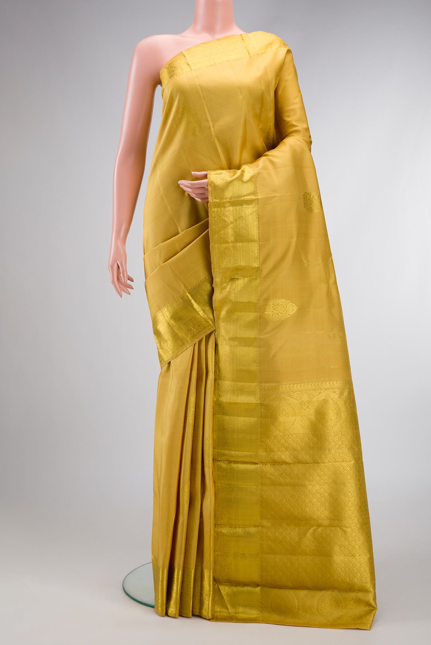 Gold Dual Tone Kanjivaram Silk Saree with Zari Butta on the body and Zari Border.  displayed on a mannequin