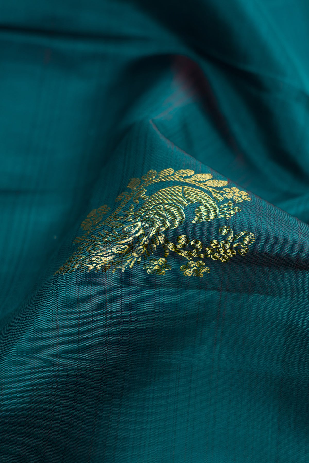 Close up of Teal Dual Tone Kanjivaram Silk Saree with Zari Butta on the body and Zari Border.  displaying folds