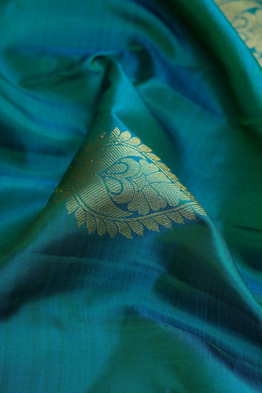 Close up of Peacock Blue Dual Tone Kanjivaram Silk Saree with Zari Butta on the body and Zari Border.  displaying folds