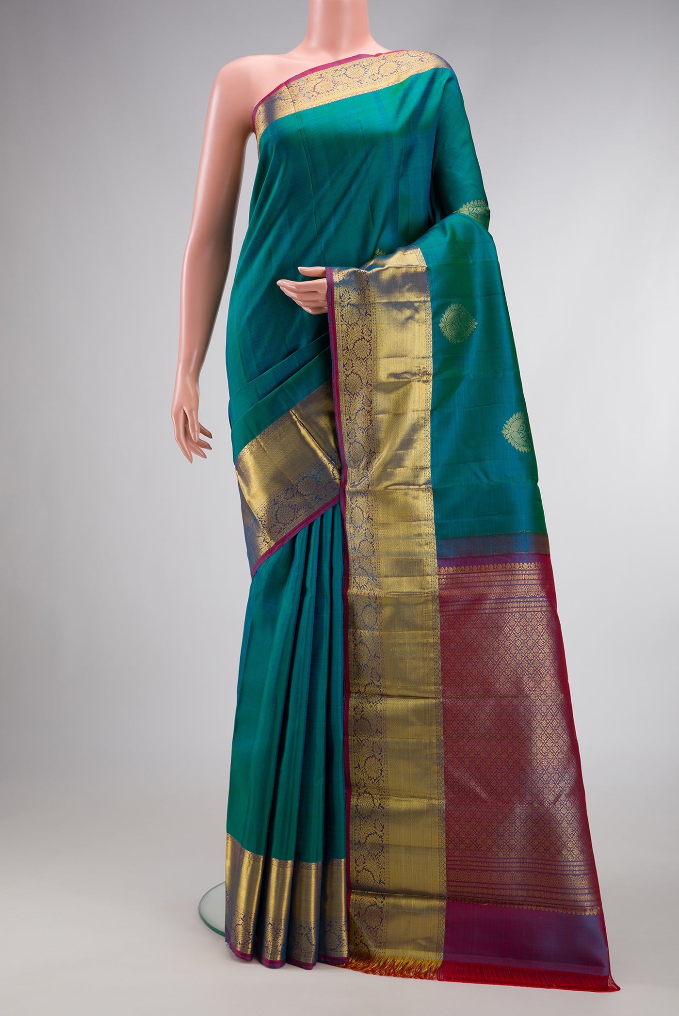 Peacock Blue Dual Tone Kanjivaram Silk Saree with Zari Butta on the body and Zari Border.  displayed on a mannequin