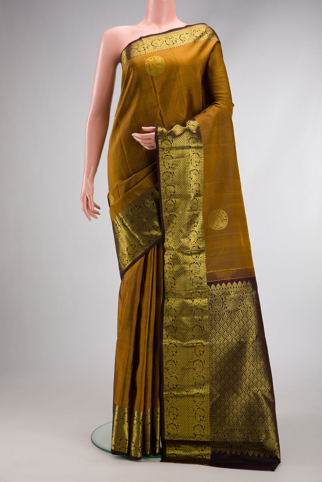 Gold Dual Tone Kanjivaram Silk Saree with Zari Butta on the body and Zari Border.  displayed on a mannequin