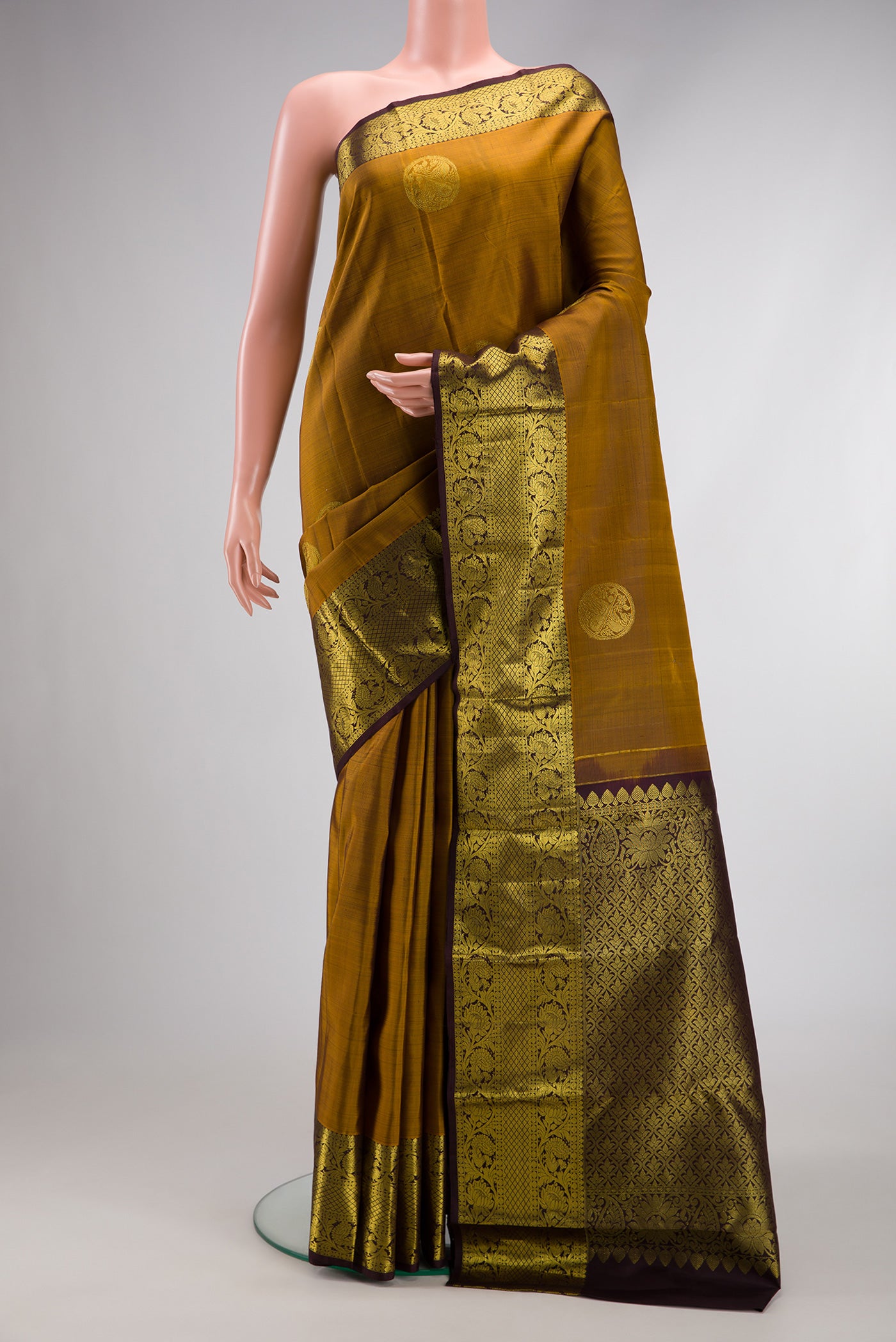 Gold Dual Tone Kanjivaram Silk Saree with Zari Butta on the body and Zari Border.  displayed on a mannequin