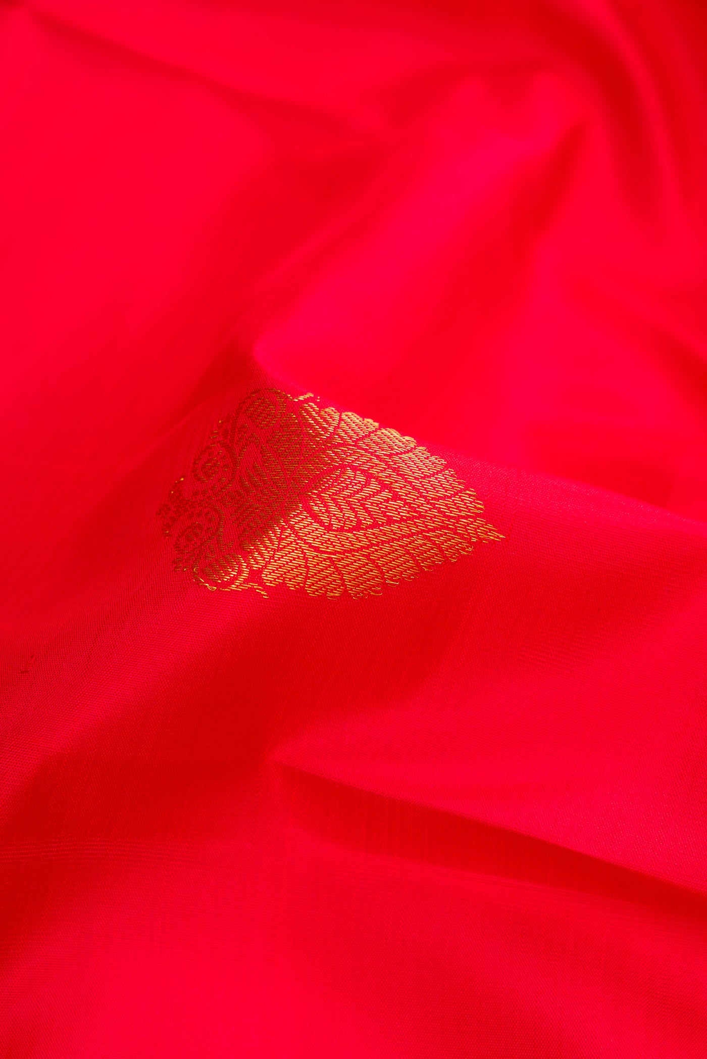 Close up of Red Dual Tone Kanjivaram Silk Saree with Zari Butta on the body and Zari Border.  displaying folds