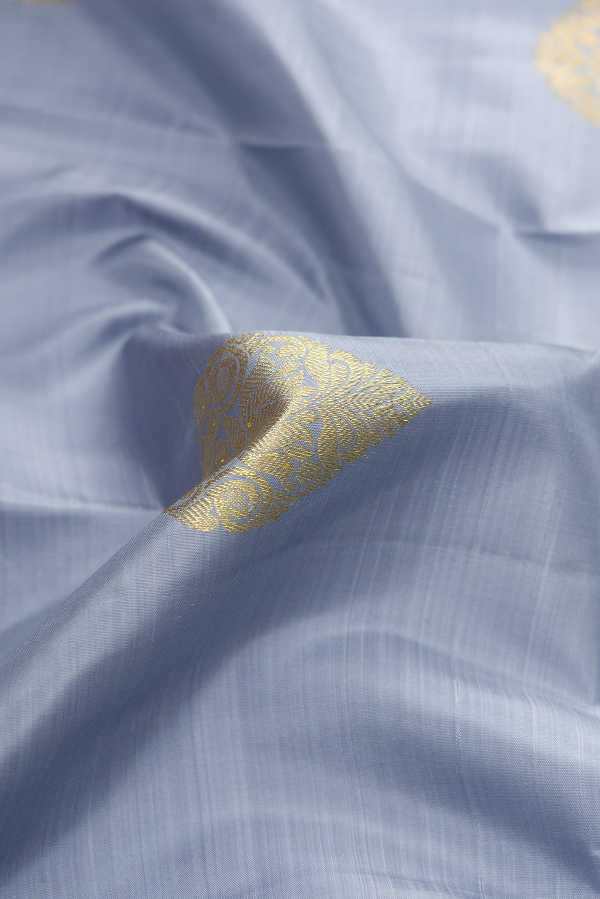 Close up of Grey Dual Tone Kanjivaram Silk Saree with Zari Butta on the body and Zari Border.  displaying folds