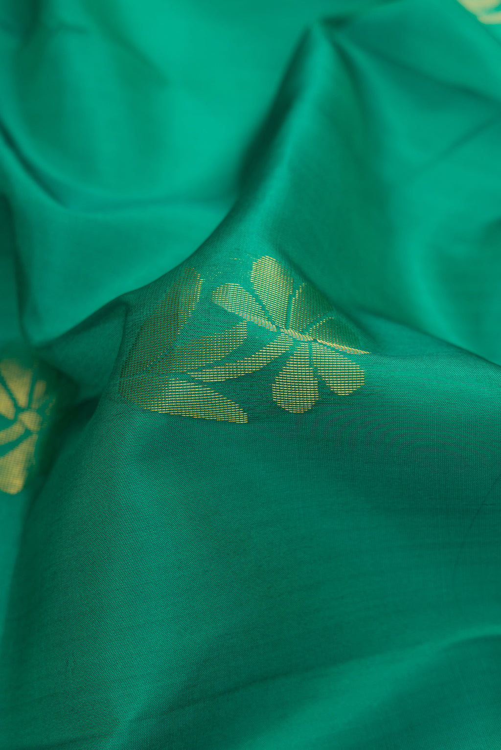 Close up of Green Dual Tone Soft Silk Saree with Zari Butta on the body and Fancy Border.  displaying folds
