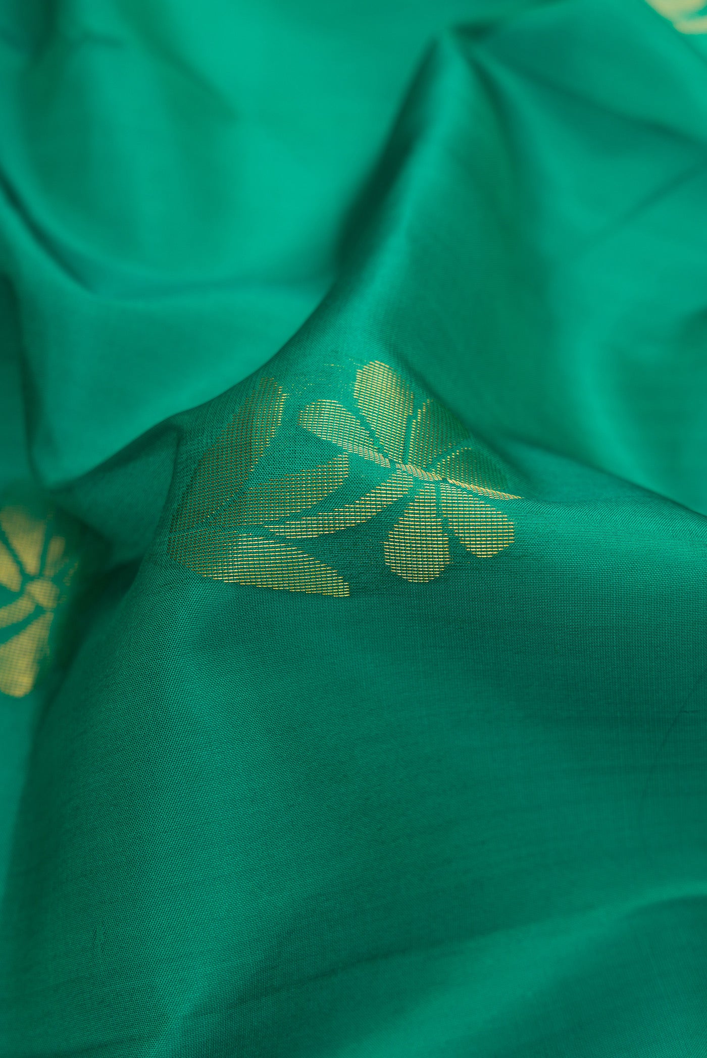 Close up of Green Dual Tone Soft Silk Saree with Zari Butta on the body and Fancy Border.  displaying folds