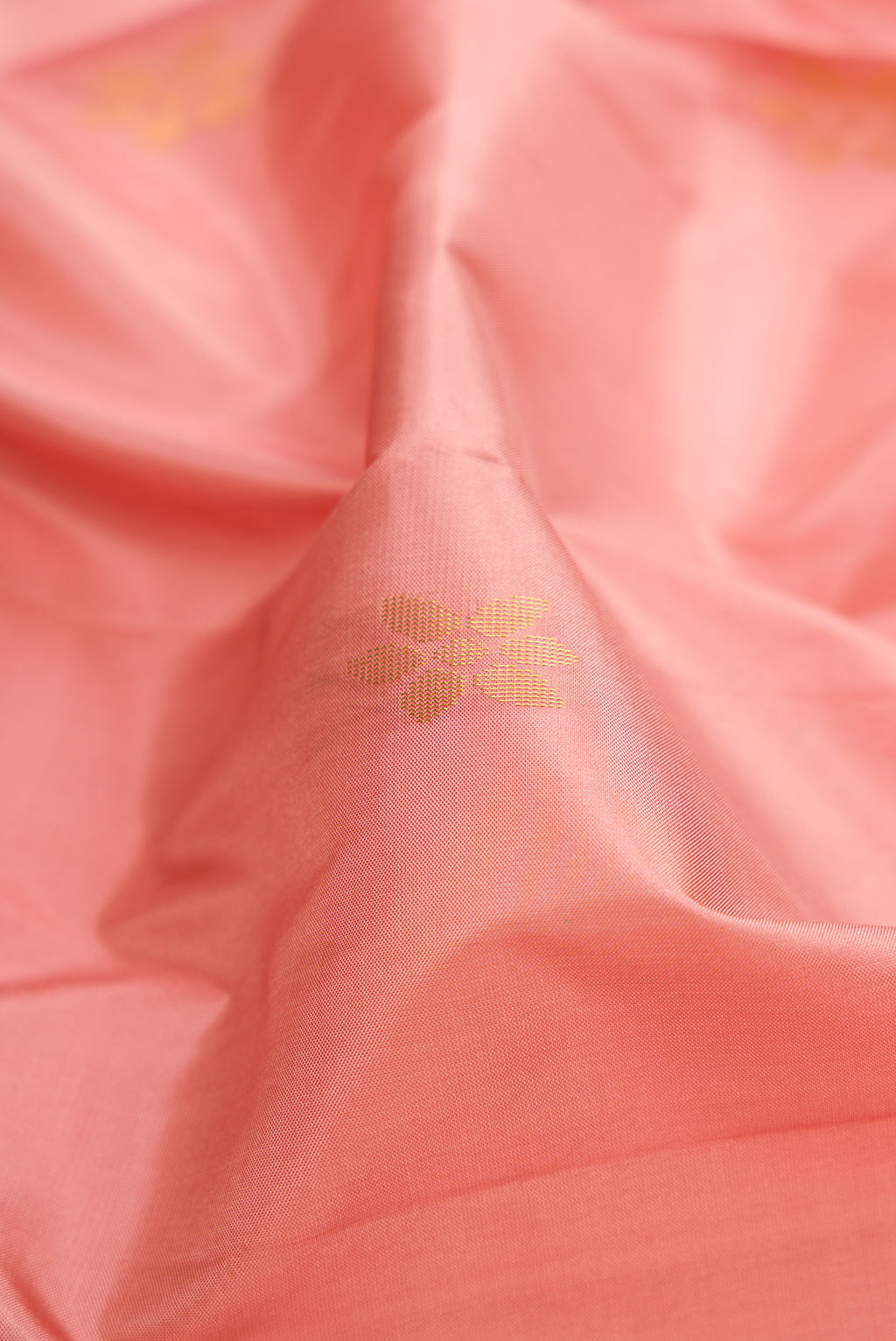 Close up of Rose Gold Soft Silk Saree with Zari Butta on the body and Fancy Border.  displaying folds