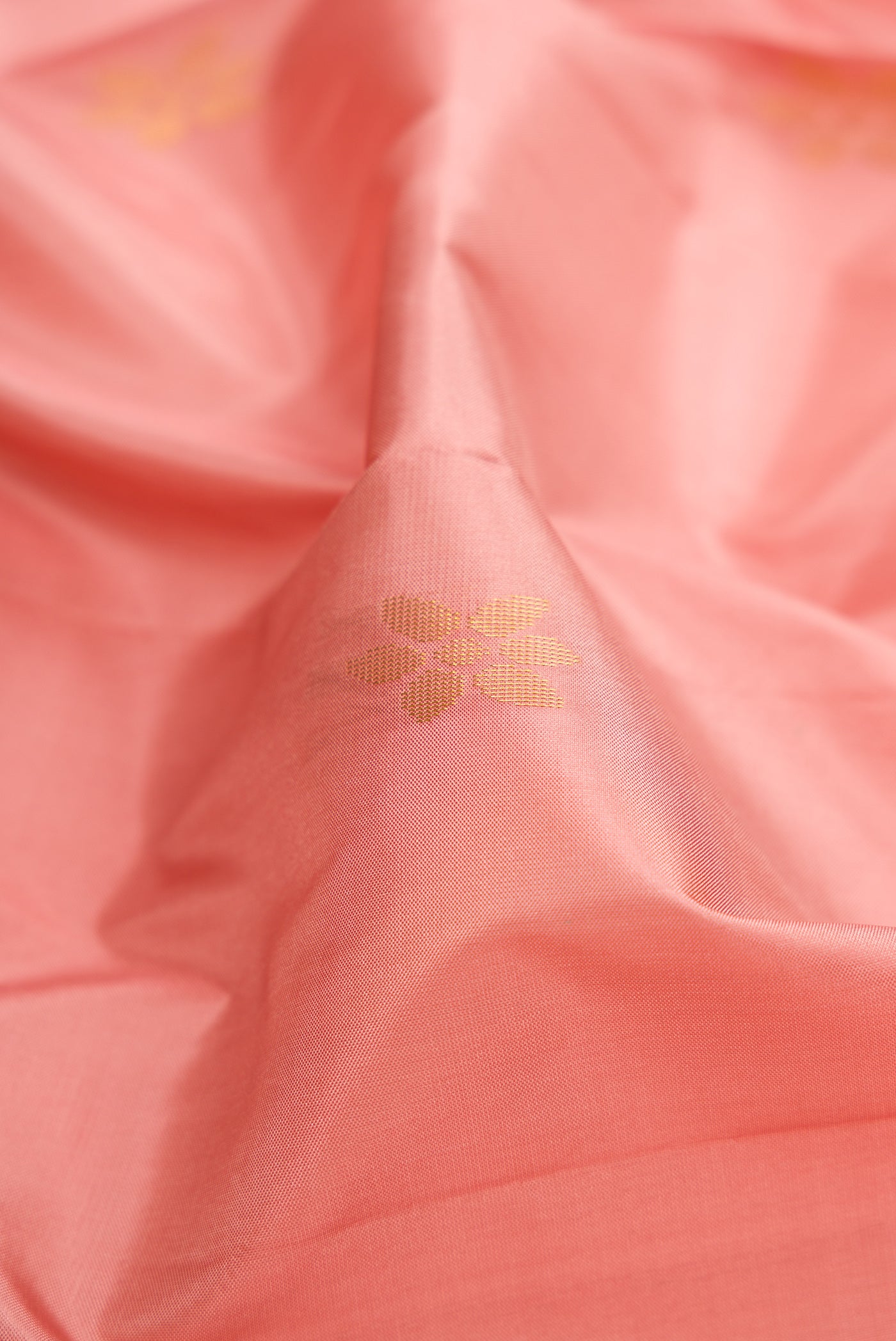 Close up of Rose Gold Soft Silk Saree with Zari Butta on the body and Fancy Border.  displaying folds