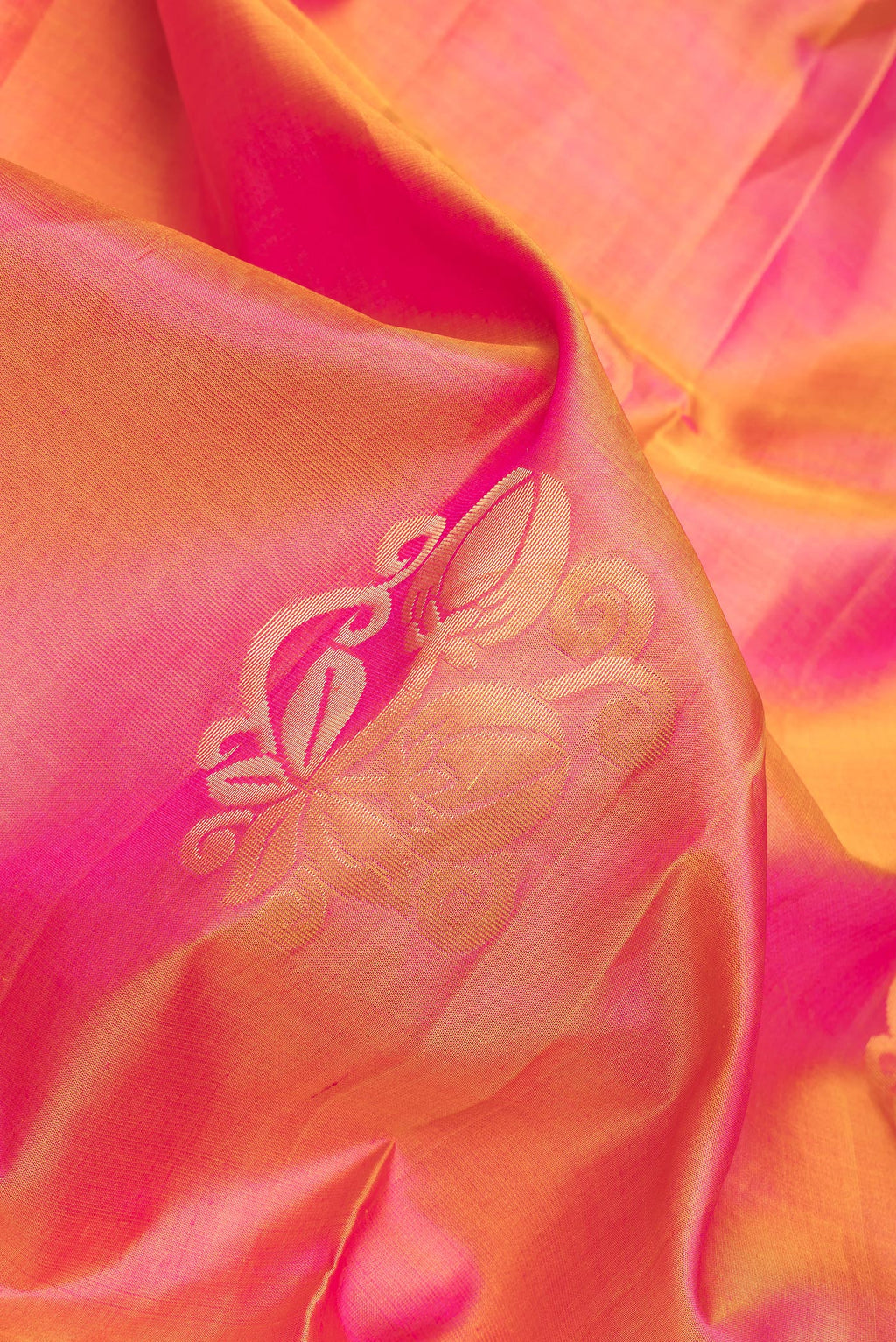 Close up of Pinkish Yellow Dual Tone Soft Silk Saree with Zari Butta on the body and Zari Border.  displaying folds