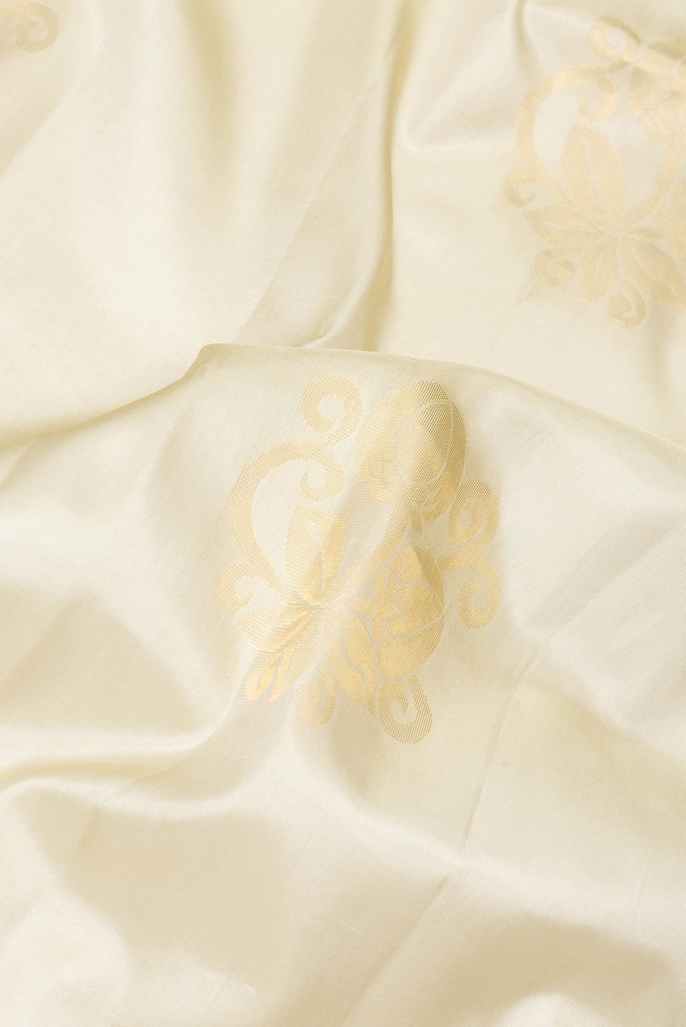 Close up of Beige Soft Silk Saree with Zari Butta on the body and Zari Border.  displaying folds