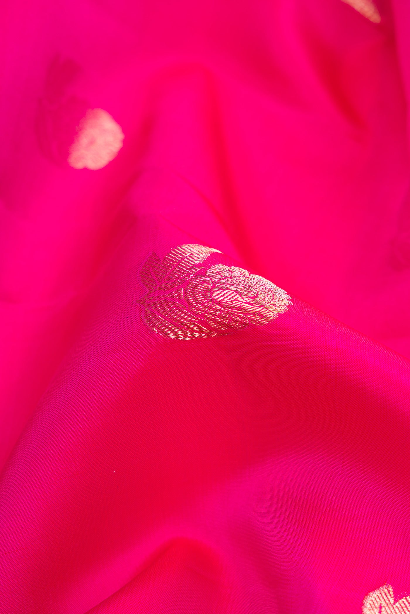 Close up of Magenta Dual Tone Kanjivaram Silk Saree with Zari Butta on the body and Zari Border.  displaying folds