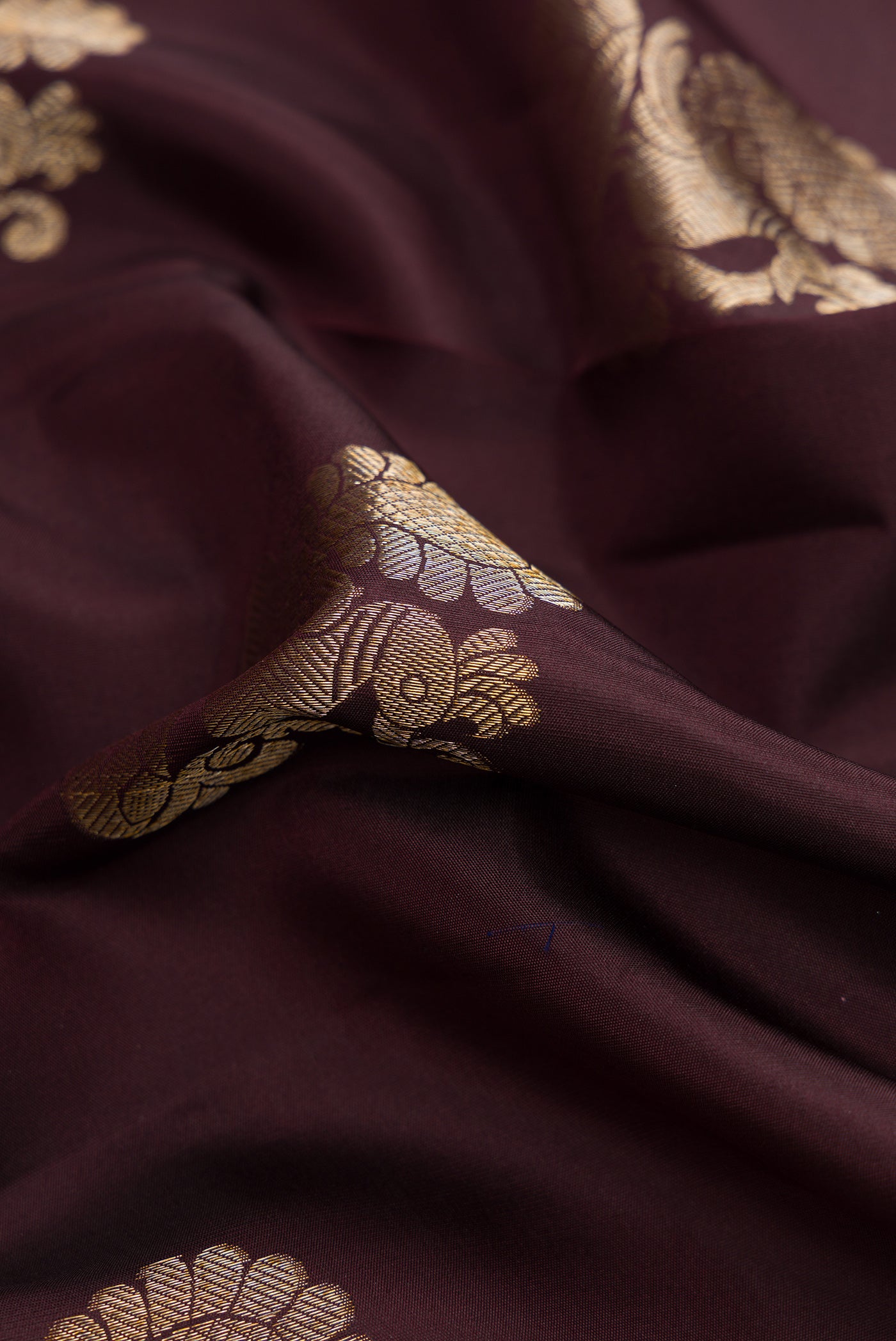 Close up of Coffee Brown Dual Tone Kanjivaram Silk Saree with Zari Butta on the body and Zari Border.  displaying folds