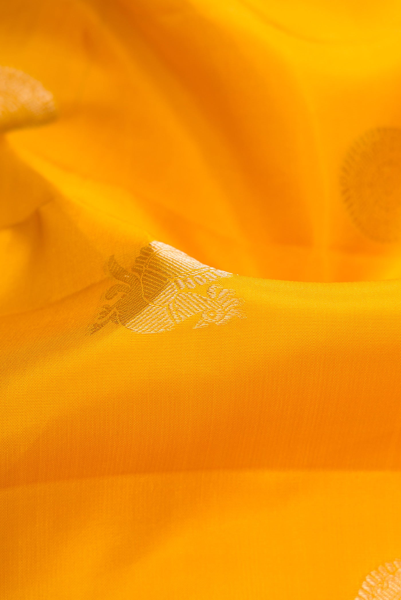 Close up of Yellow Dual Tone Kanchipuram Silk Saree with Zari Butta on the body and Zari Border.  displaying folds