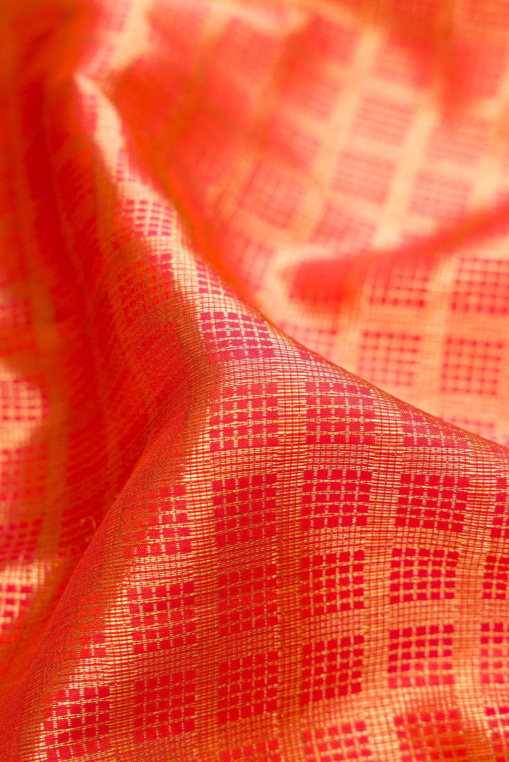 Close up of Orange Dual Tone Kanchipuram Silk Saree with Checked design on the body and Zari Border.  displaying folds