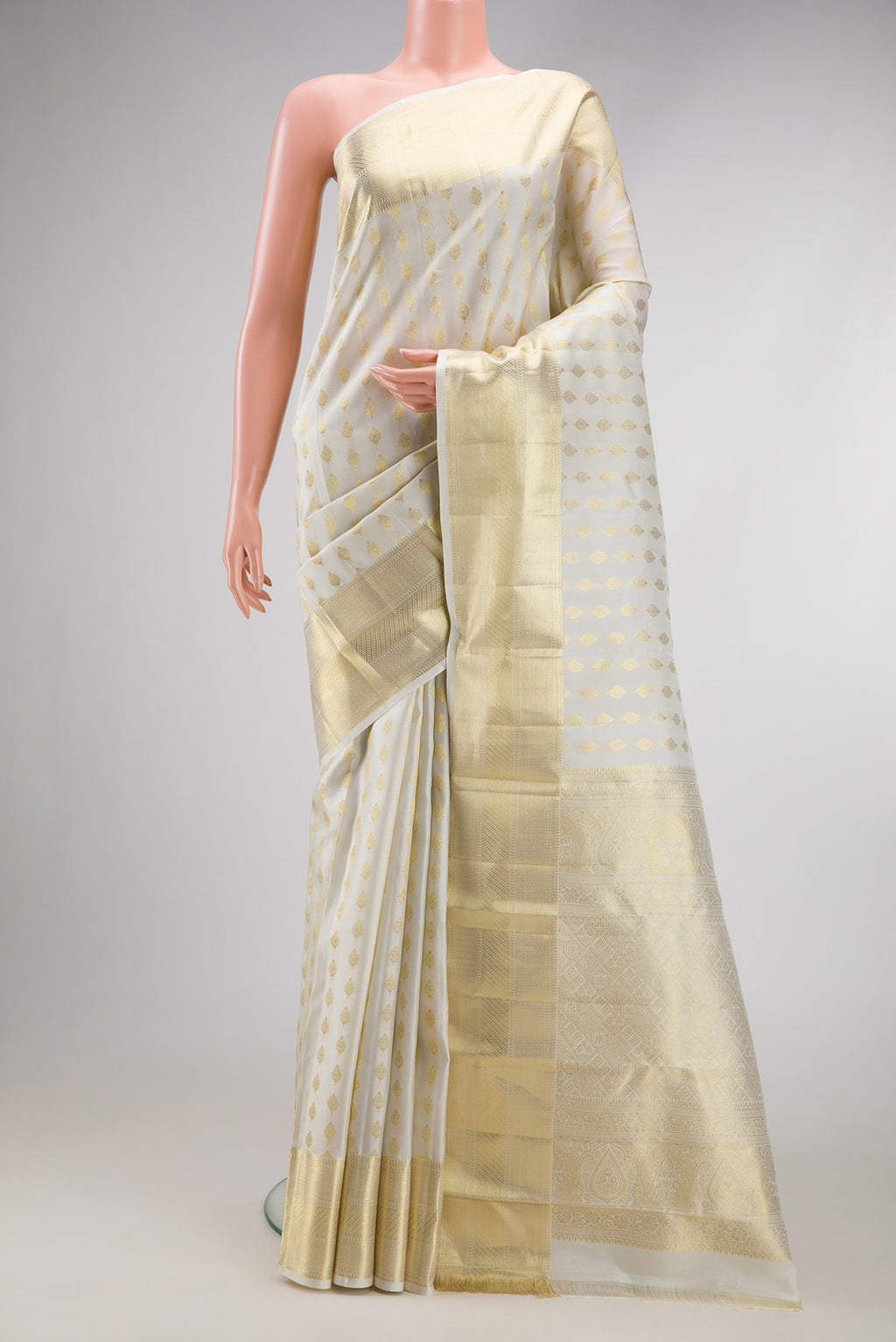 Off White Kanchipuram Silk Saree with Zari Butta on the body and Zari Border.  displayed on a mannequin