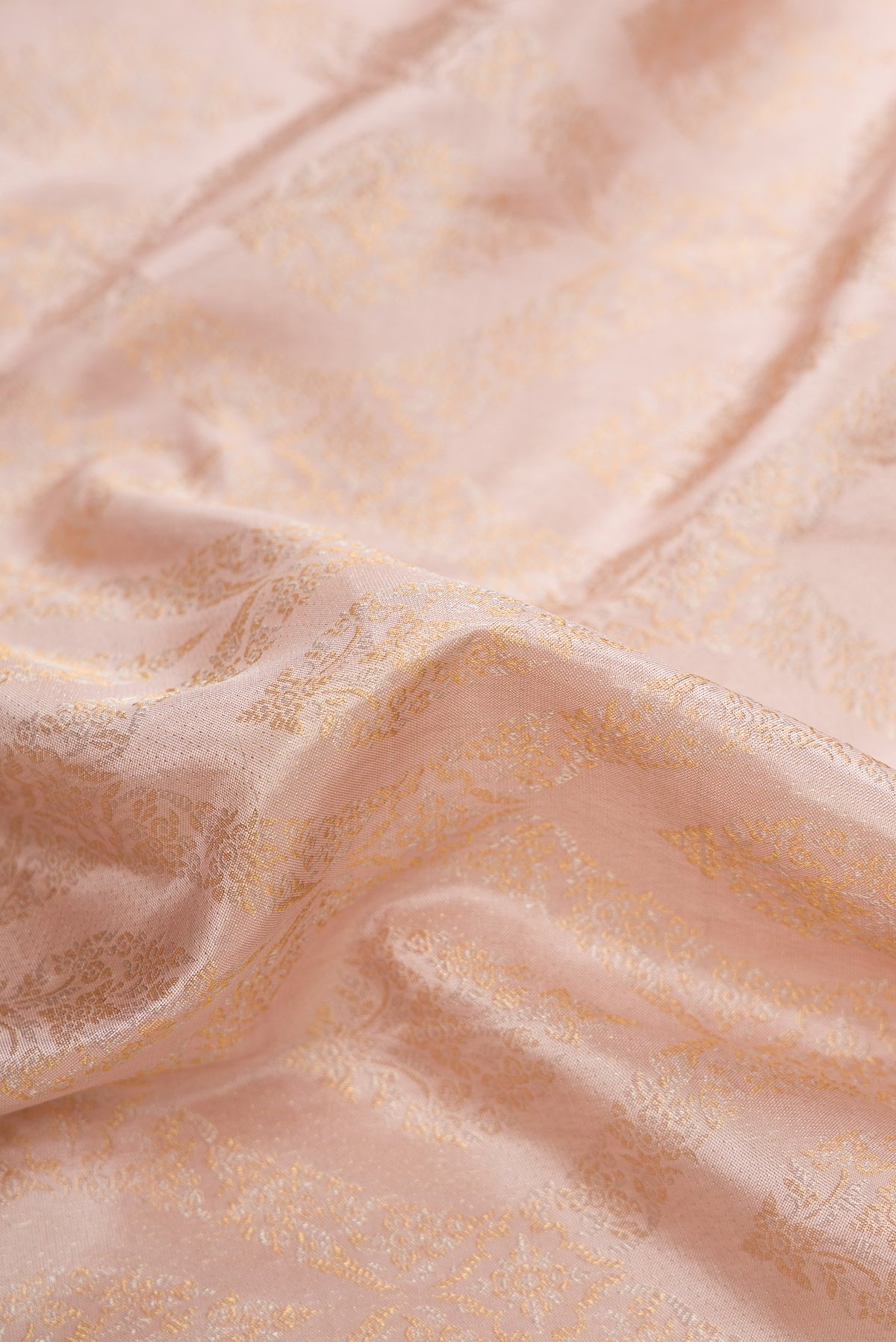Close up of Rose Gold Dual Tone Kanchipuram Silk Saree with Zari Brocade on the body and Zari Border.  displaying folds