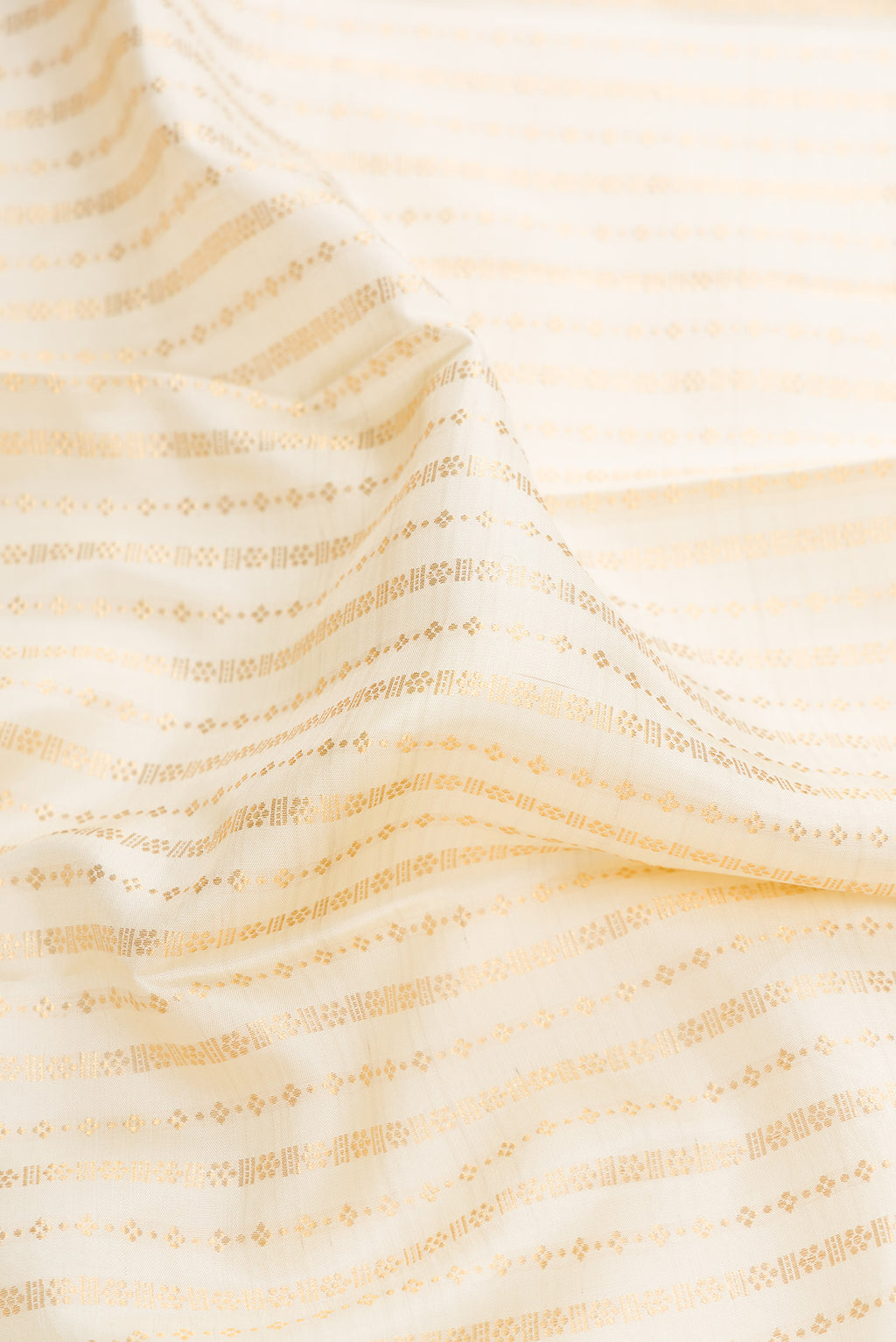 Close up of Off White Dual Tone Kanchipuram Silk Saree with Zari Brocade on the body and Zari Border.  displaying folds