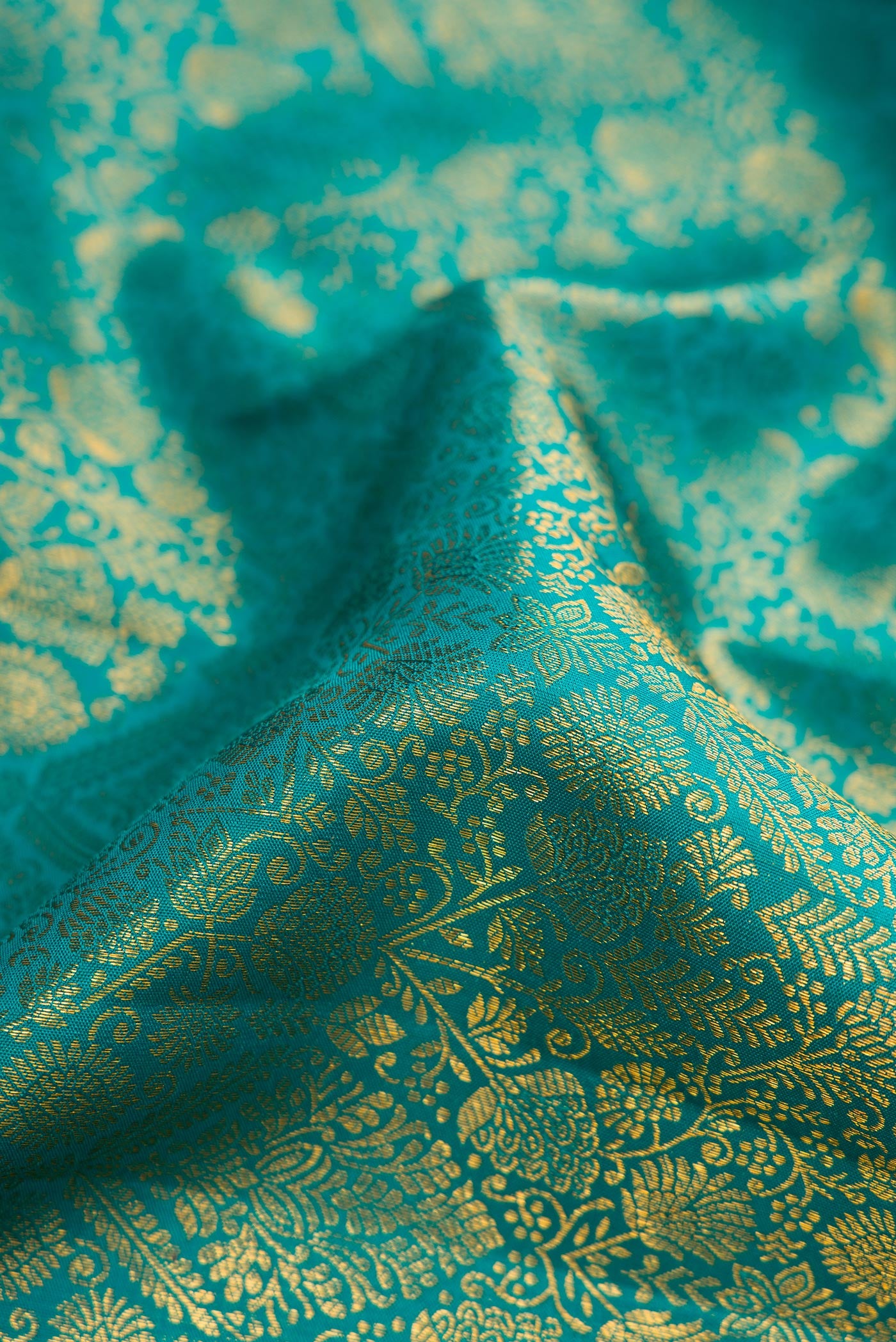 Close up of Peacock Blue Dual Tone Kanchipuram Silk Saree with Zari Brocade on the body and Zari Border.  displaying folds
