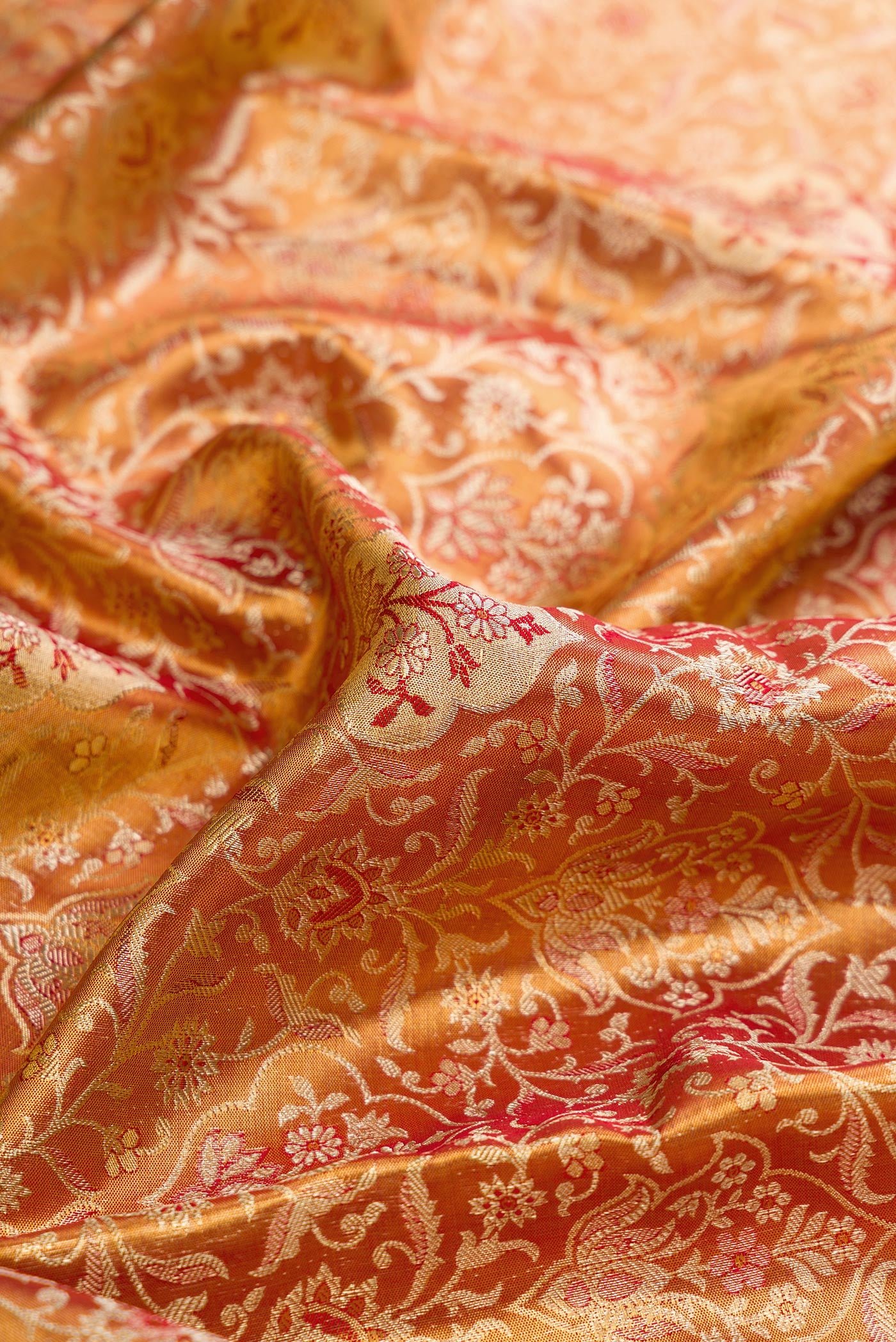Close up of Red Dual Tone Kanjivaram Tissue Silk Saree with Zari Brocade on the body and Zari Border.  displaying folds