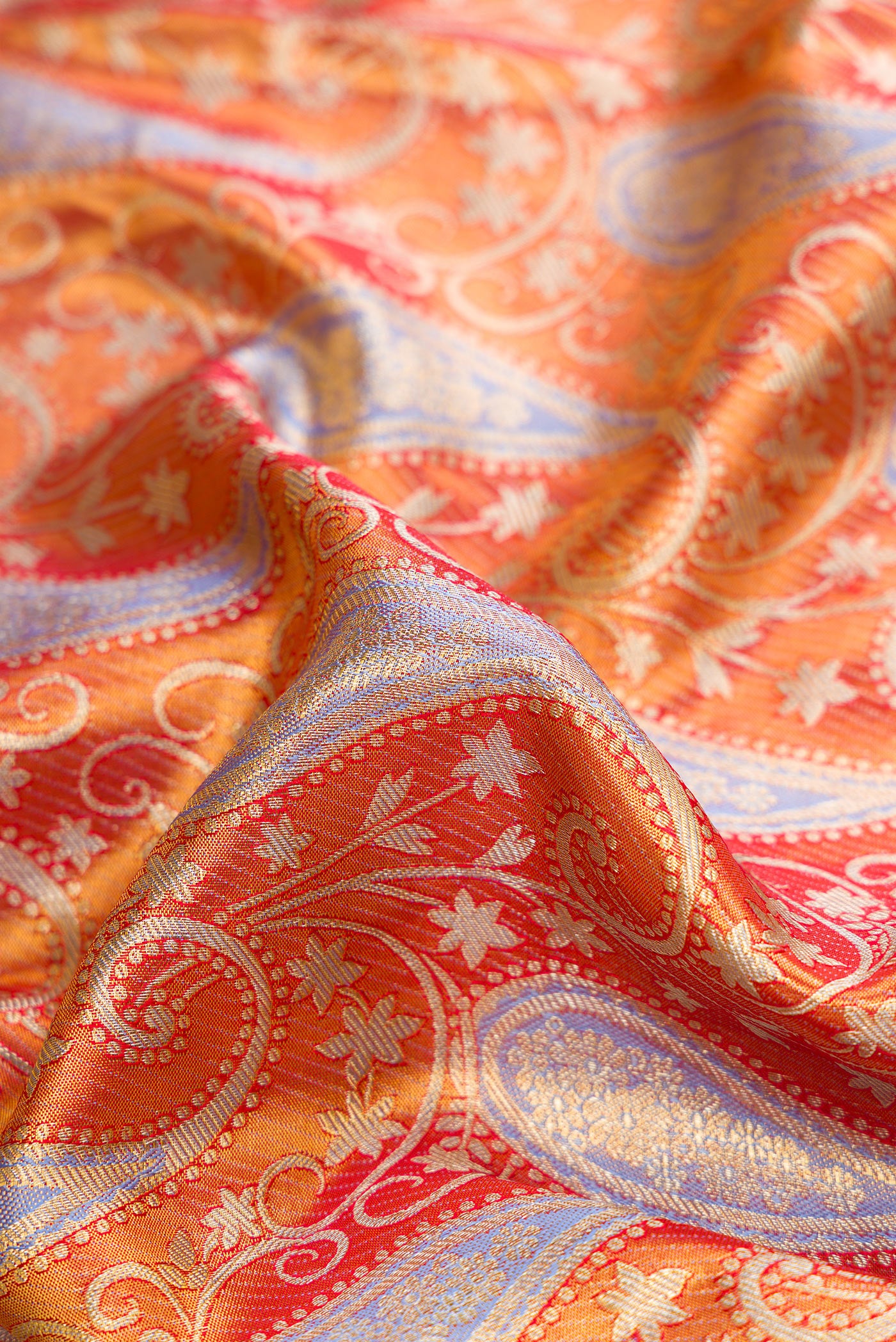 Close up of Orange Dual Tone Kanjivaram Tissue Silk Saree with Zari Brocade on the body and Fancy Border.  displaying folds