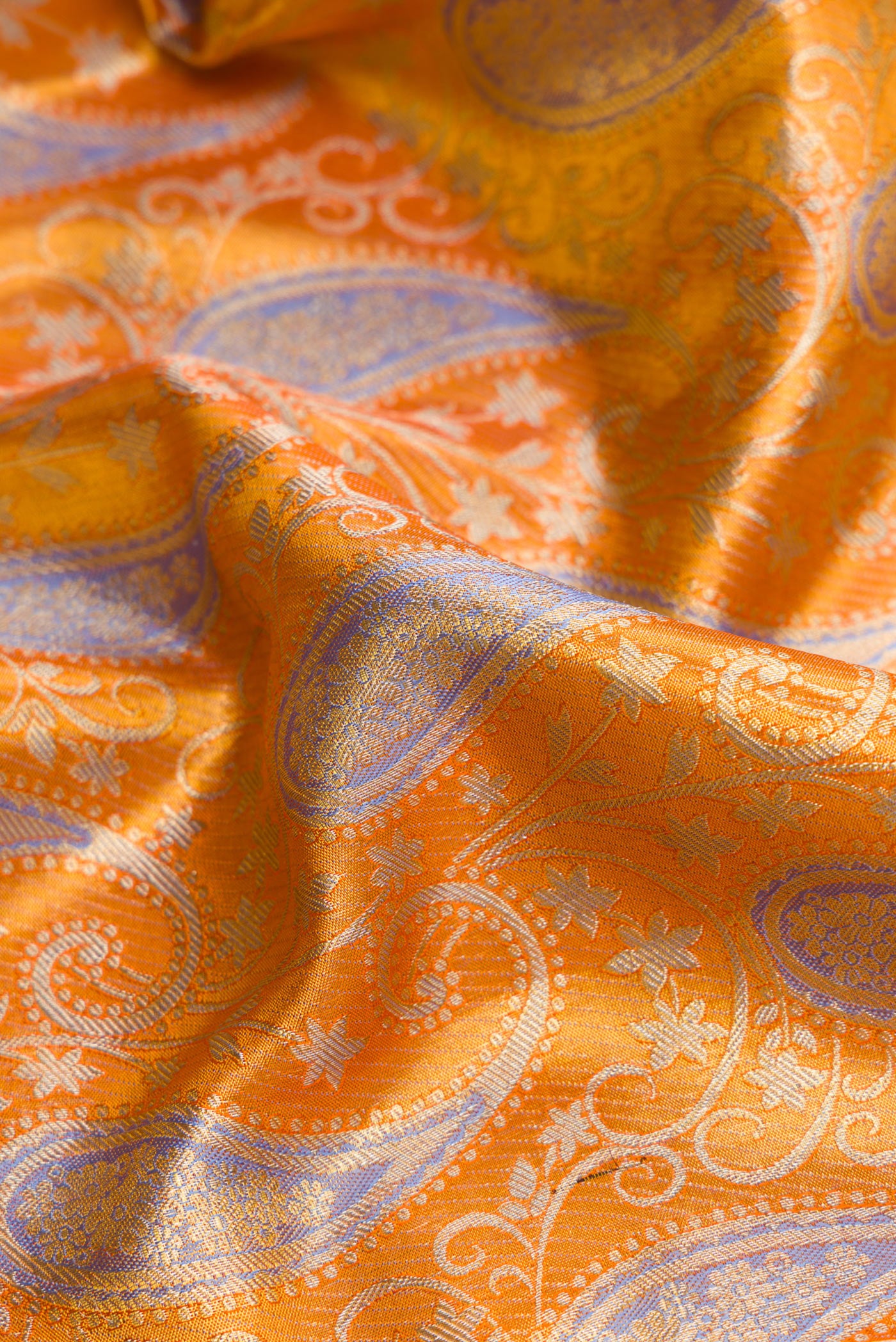 Close up of Orange Dual Tone Kanjivaram Tissue Silk Saree with Zari Brocade on the body and Zari Border.  displaying folds