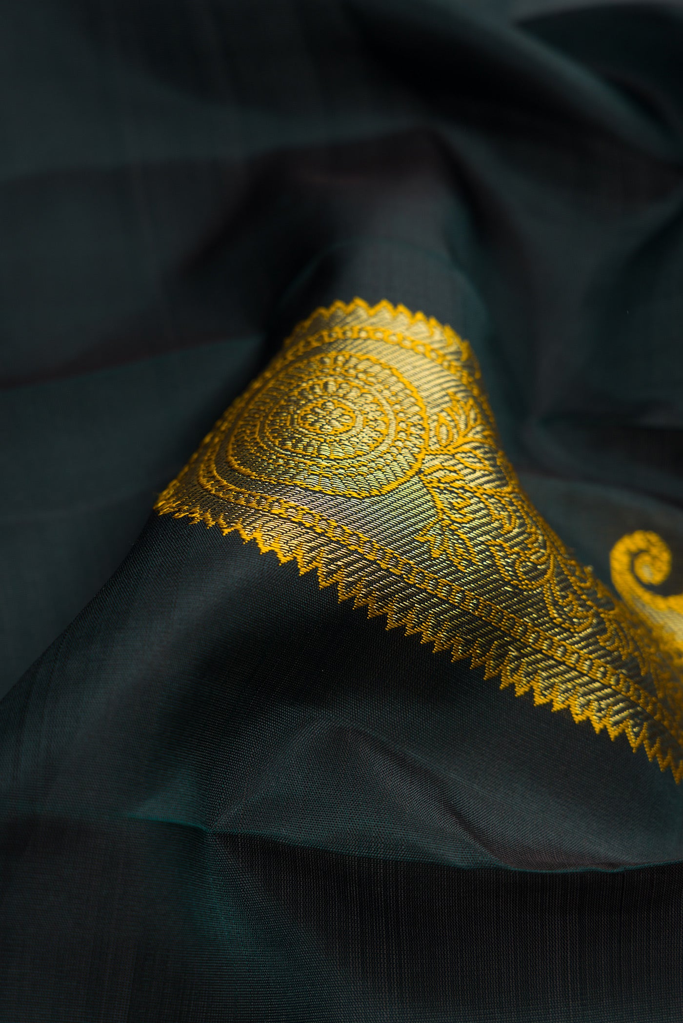 Close up of Bottle Green Dual Tone Kanchipuram Silk Saree with Zari And Thread Butta on the body and Without Border.  displaying folds