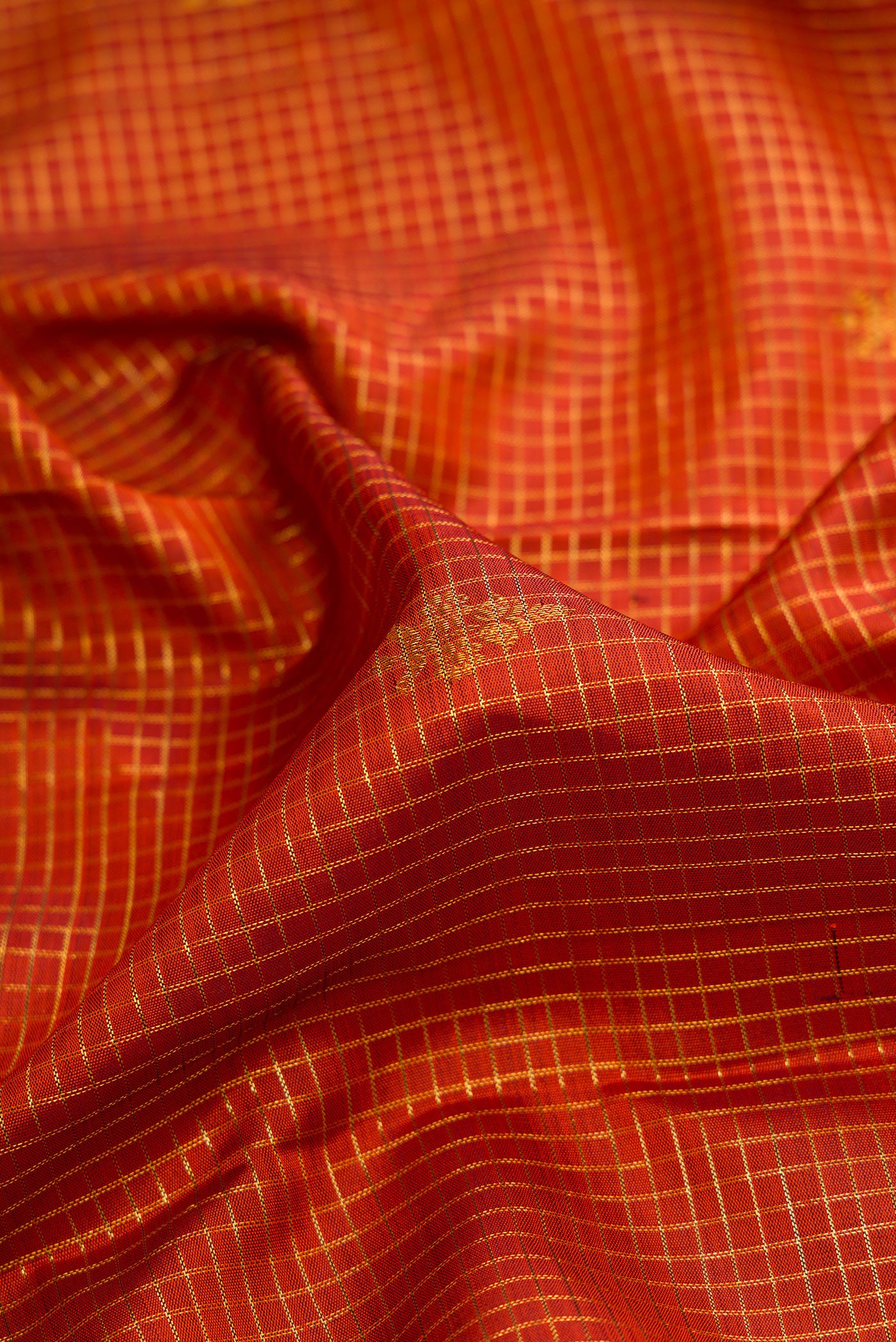 Close up of Orange Dual Tone Kanchipuram Silk Saree with Checked design on the body and Zari Border.  displaying folds